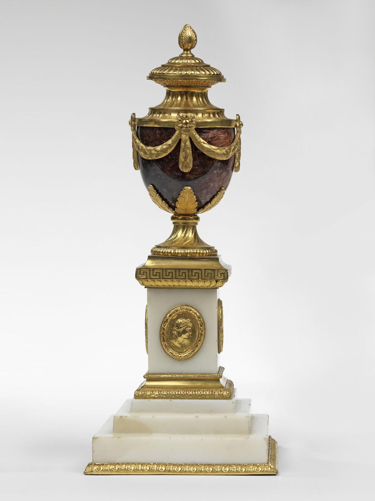 Each with a stamped three-step white marble pedestal, decorated with medallions of Ceres. The stamped Greek fret frieze round the top of the pedestal, the stem with spiral flutes, the acanthus leaf cradle holding the blue john vase body, and,