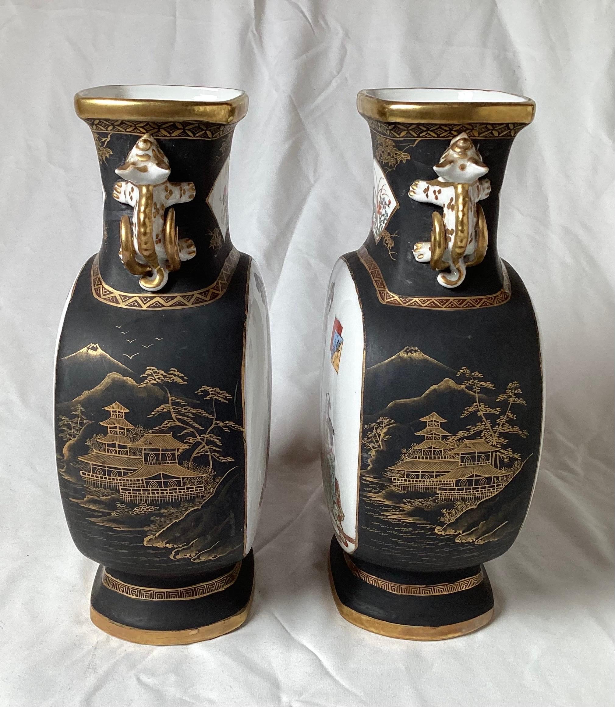A pair of hand painted Japanese Moon vases with foo dog handles. The porcelain vases with hand painted 
Geisha figures on both sides, the fronts with an ivory white porcelain with the tops, sides and bottoms with a matt black with gold painted