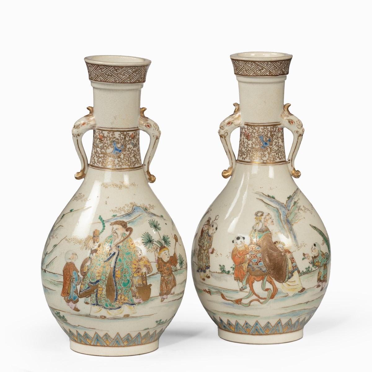 A pair of Meiji period Satsuma earthenware vases, each with applied elephant-mask handles, painted in overglaze pastel enamels and gilt with a continuous central frieze of sages and children in a mountainous landscape, with a border of scrolling