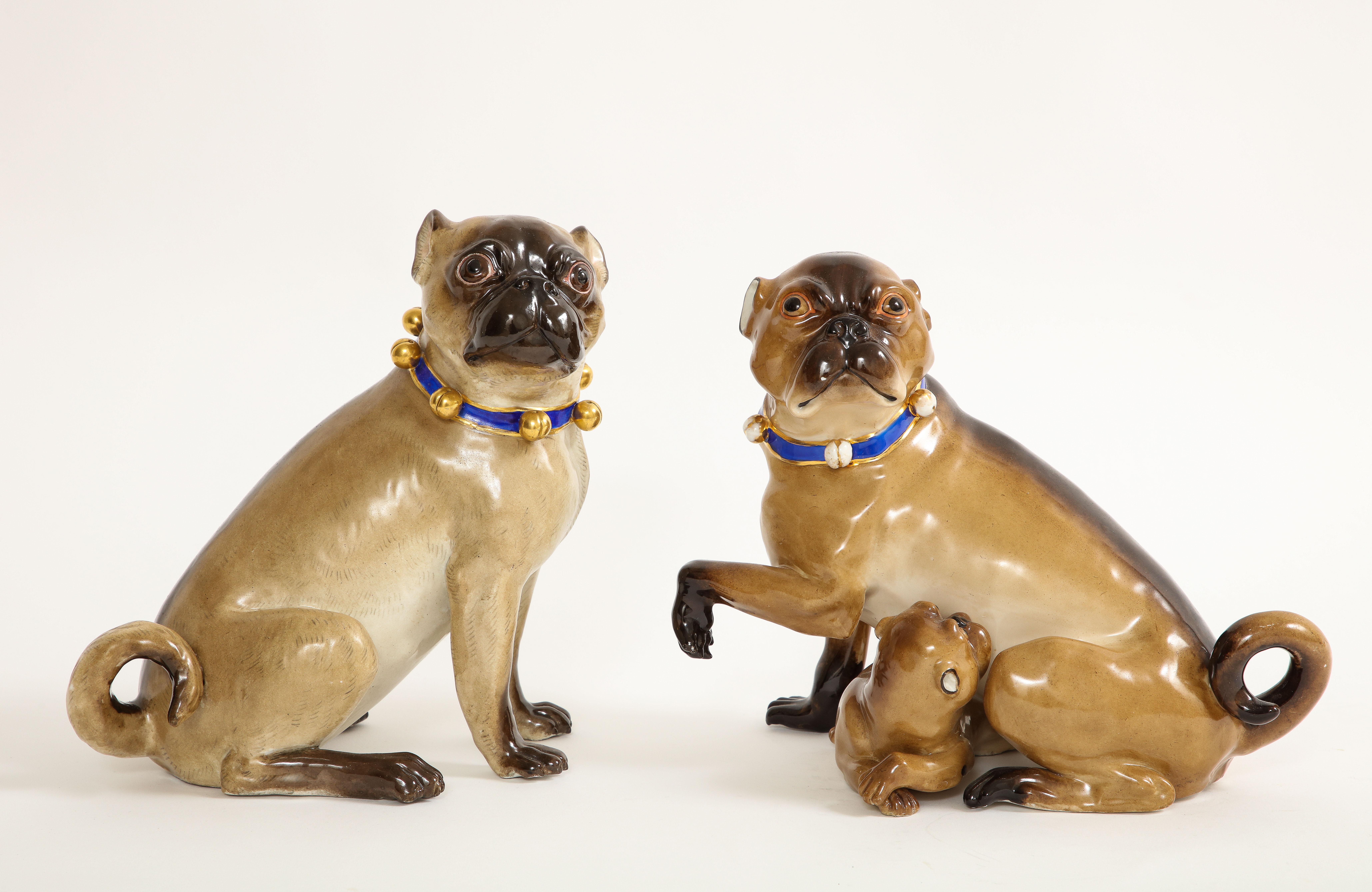 Splendida coppia di figure in porcellana di Meissen Porcelain del XIX secolo con collari a campana dorati e nastri in porcellana blu, un cane con un bambino. Squisitamente dipinto a mano con toni e colori realistici. Ogni carlino indossa un collare