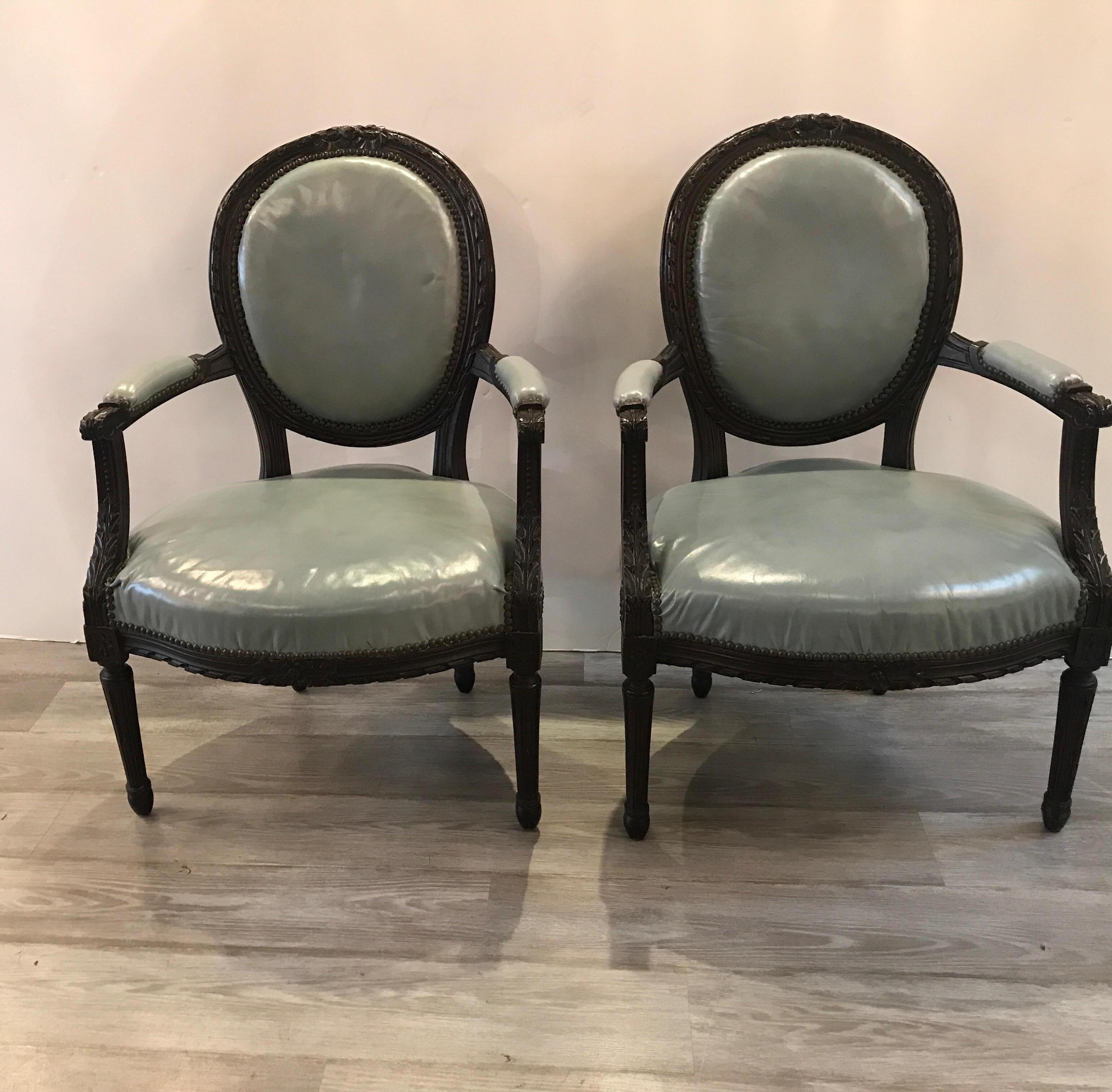 Beautiful hand carved dark walnut Louis XVI style armchairs from the mid-19th century. The Classic form with hand carved detail all around with robins egg blue leather in good condition but new upholstery will make this pair of chairs exceptional.
