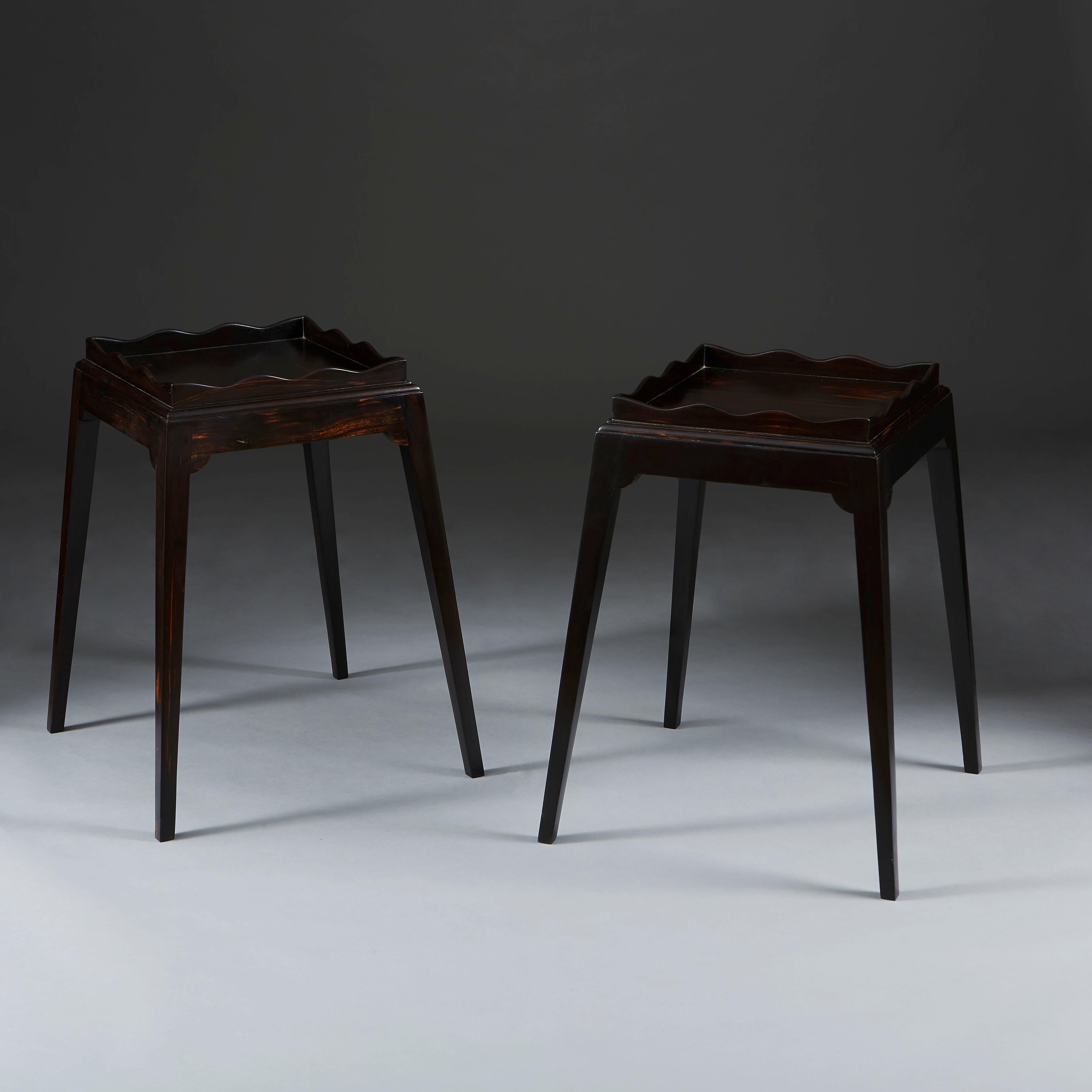 A pair of 20th century ebony square occasional tables, the tops bordered with undulating galleries, supported on four tapering legs.
 
  