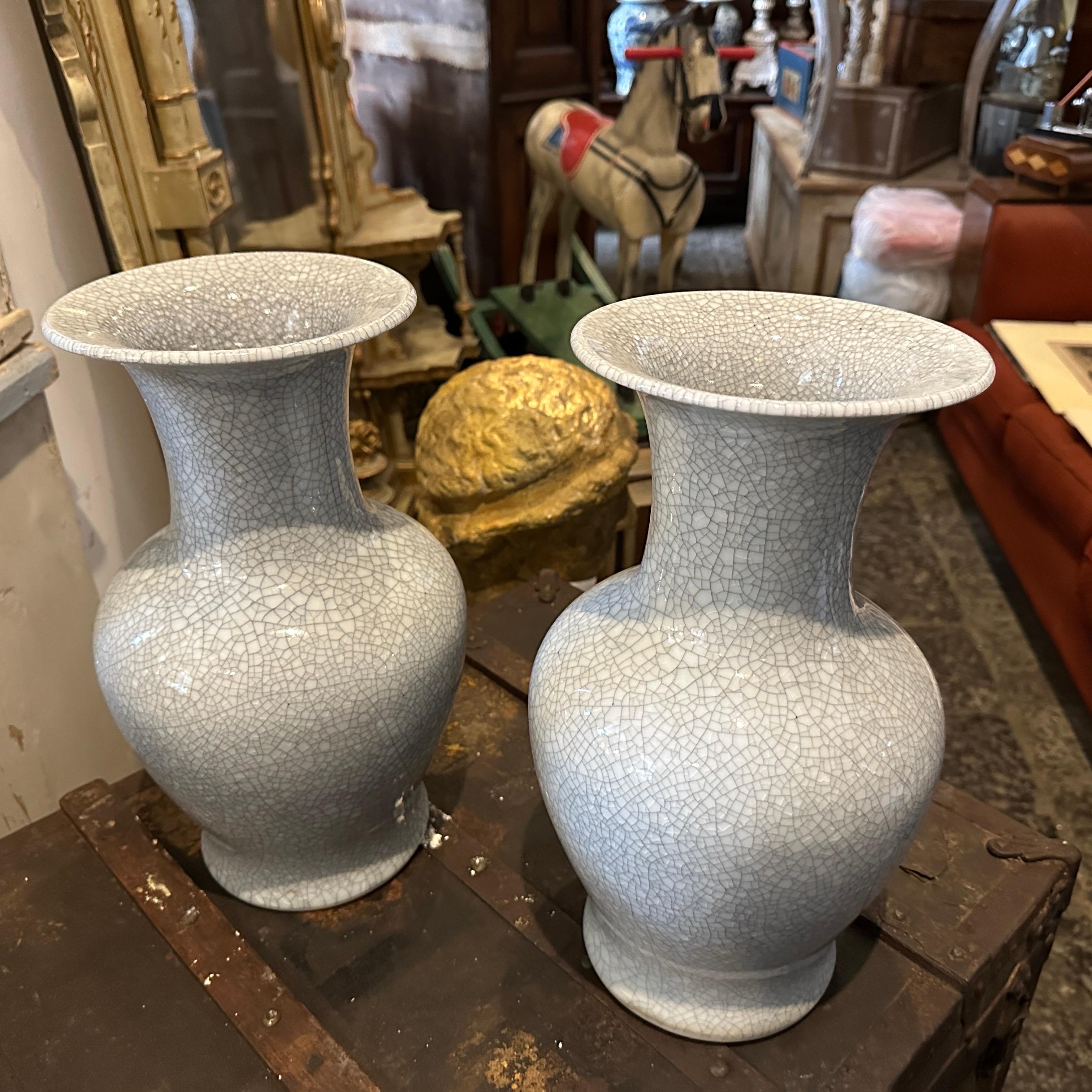 A pair of simple and elegant well shaped Celadon vases manufactured in China in the Mid-20th Century, the vases are covered overall with a crackled grey celadon glaze. The glaze it's smooth and even, with a slight sheen that catches the light.