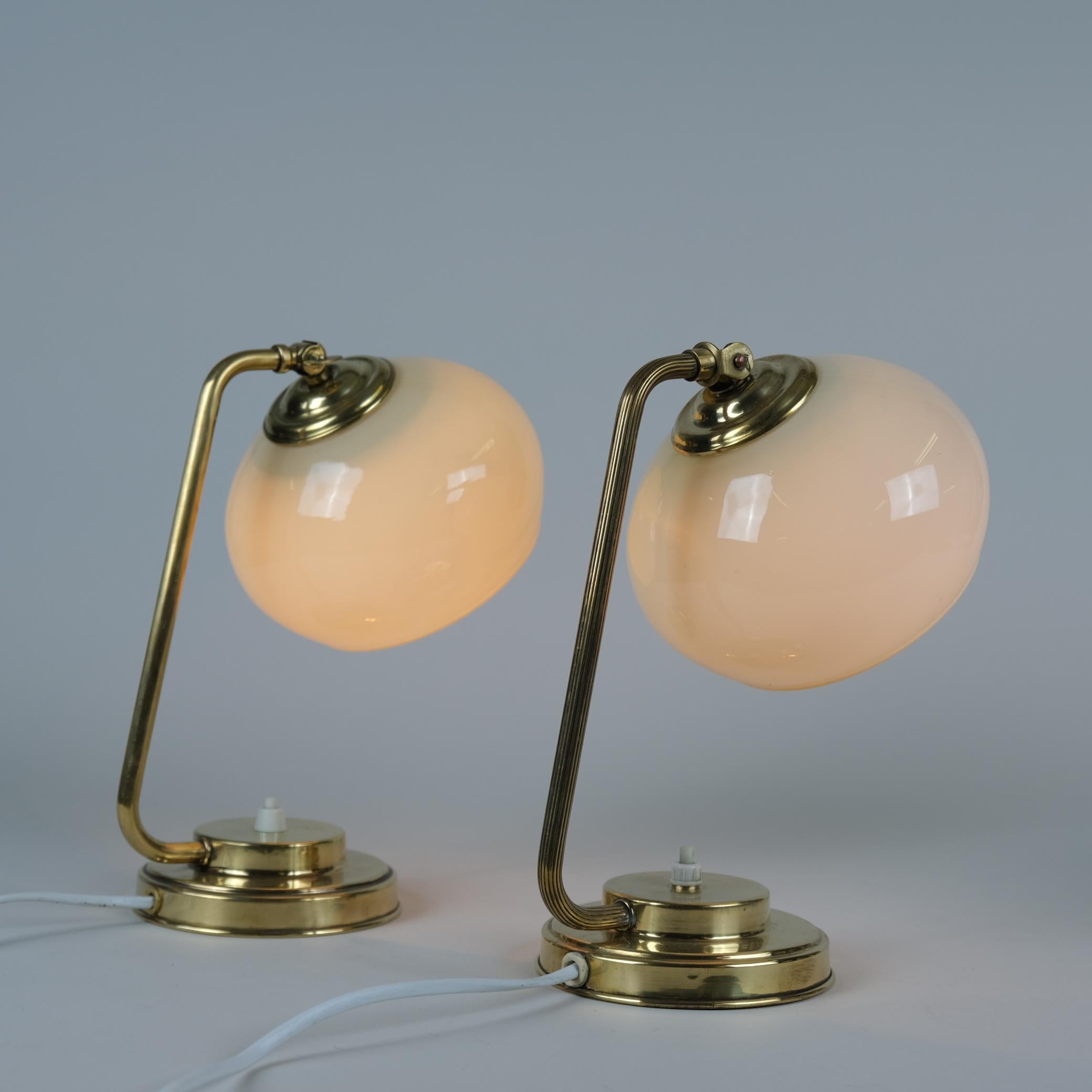 Une belle paire de lampes de table en laiton et verre soufflé modèle EV53 fabriquée par Itsu en Finlande dans les années 1950. Les abat-jours en verre ont un ton beige et ajoutent une belle ambiance. Parfait pour les tables d'appoint ou les tables