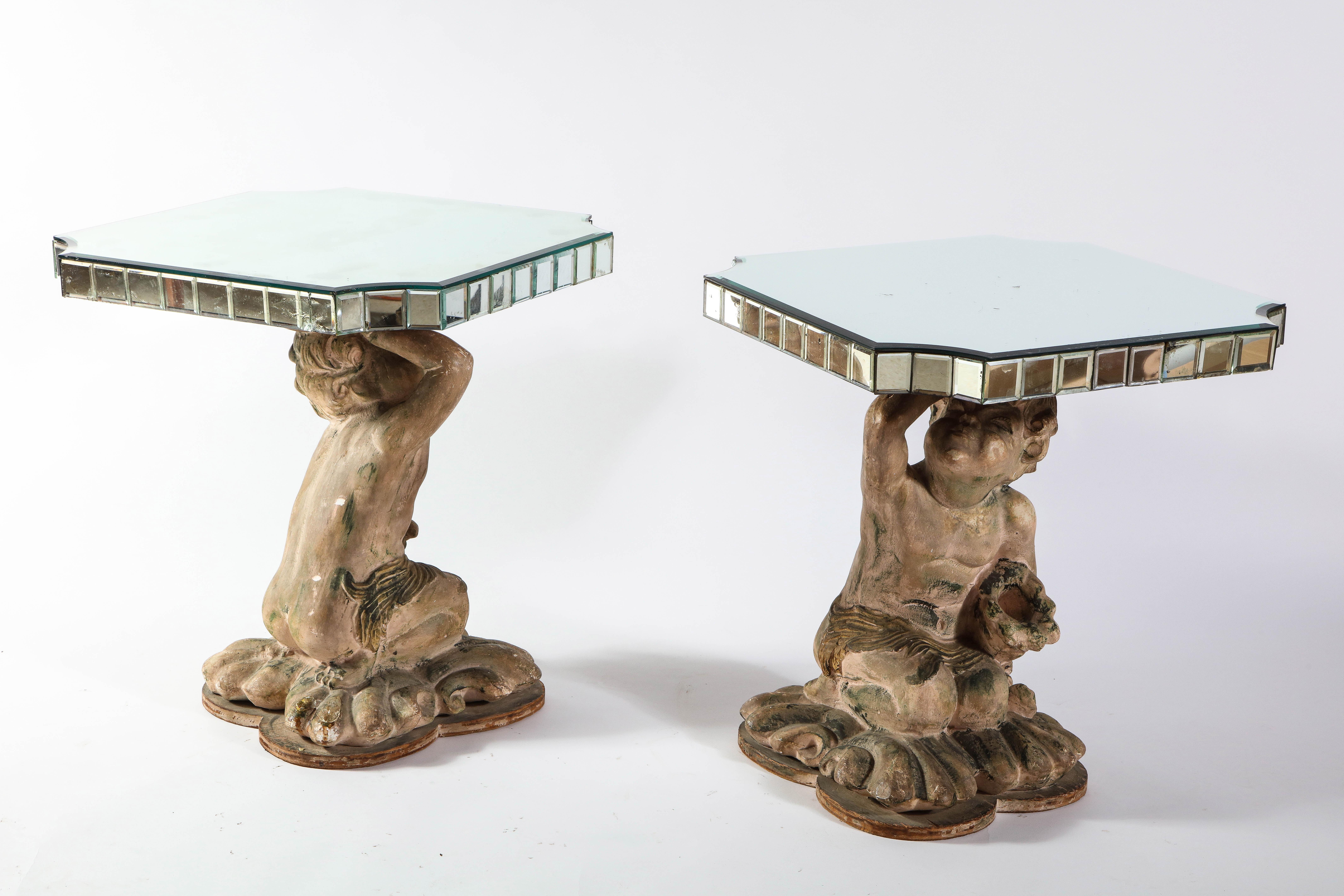 An unusual and quite decorative pair of midcentury French terracotta mirrored and figural side tables. Each cupid-like figure is made of hand carved terracotta, which is finely hand-finished with a chisel. Each cupid figure is naturalistic in