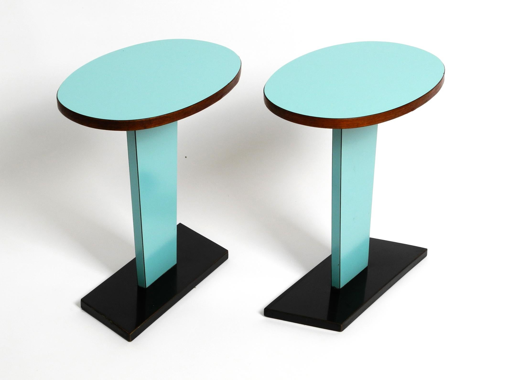 Pair of rare Italian Mid Century side tables with formica surface.
Solid wood tabletop with a turquoise Resopal surface, the edges are covered with teak veneer.
Neck and foot are with black formica.
Very nice 1950s minimalist design.
In good