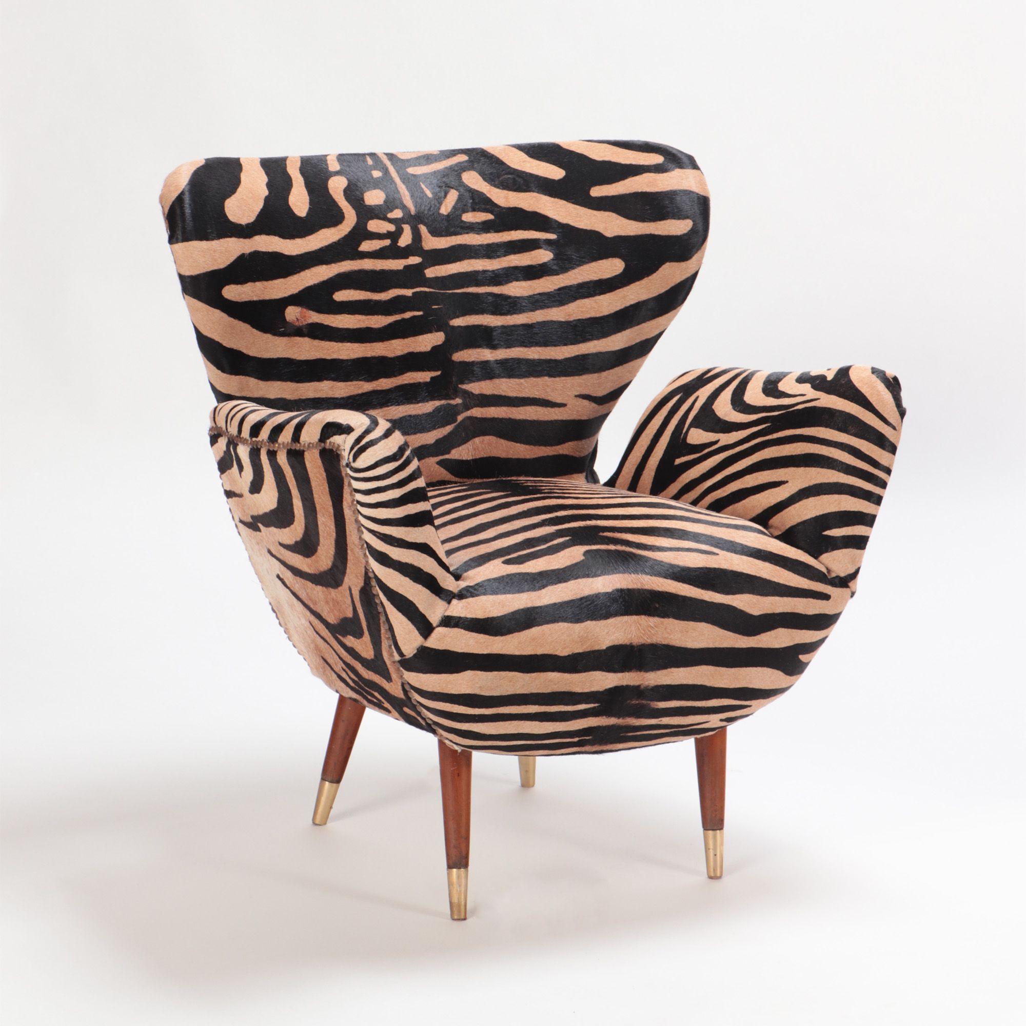 A pair of mid-century Italian wingback chairs, upholstered with zebra print leather, in the style of Paolo Buffa, circa 1950. Flared wooden legs ending with brass details.