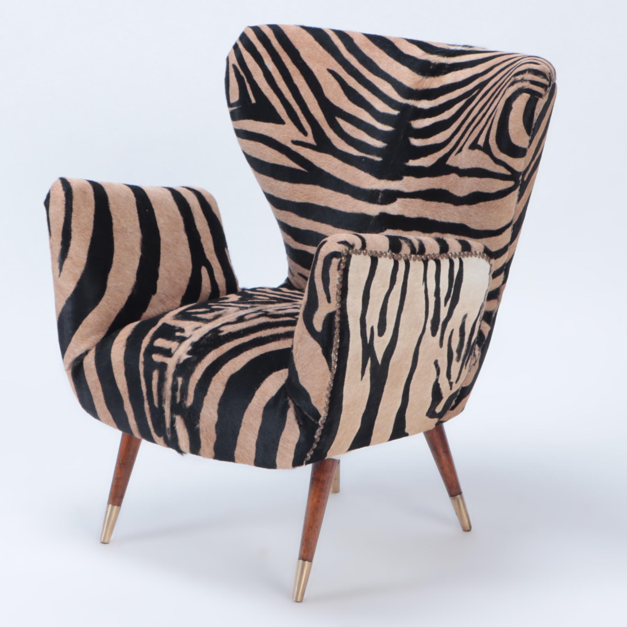 A pair of newly upholstered with zebra print leather mid-century Italian wingback chairs, in the style of Paolo Buffa, circa 1950. Flared wooden legs ending with brass details.