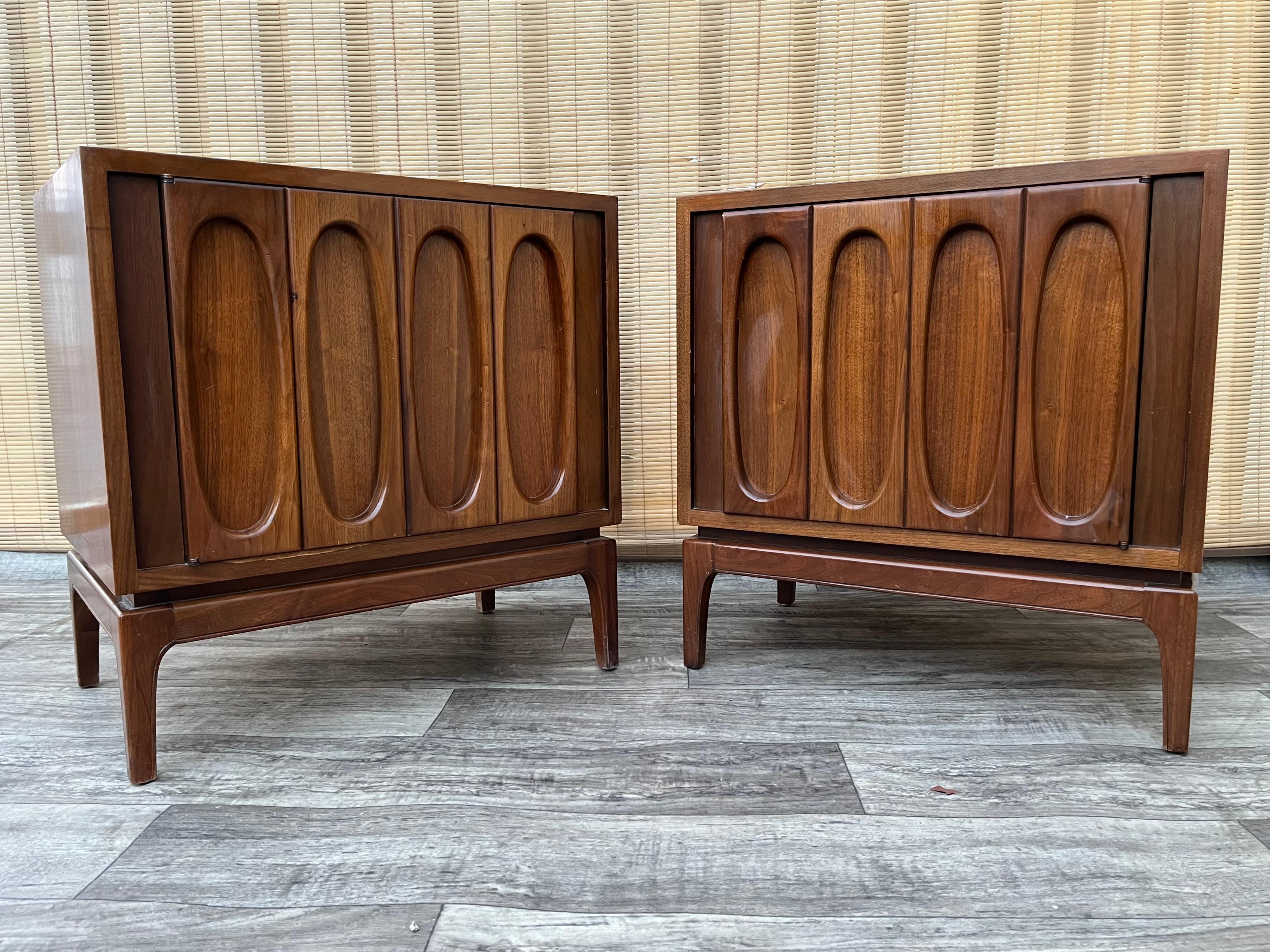 A Pair of Vintage Mid Century Modern Brutalist Inspired Nightstands. Circa 1960s.
Feature a brutalist inspired designed doors, a beautiful walnut wood grain finish, and open cabinet spaces with removable shelves.
In good original condition with