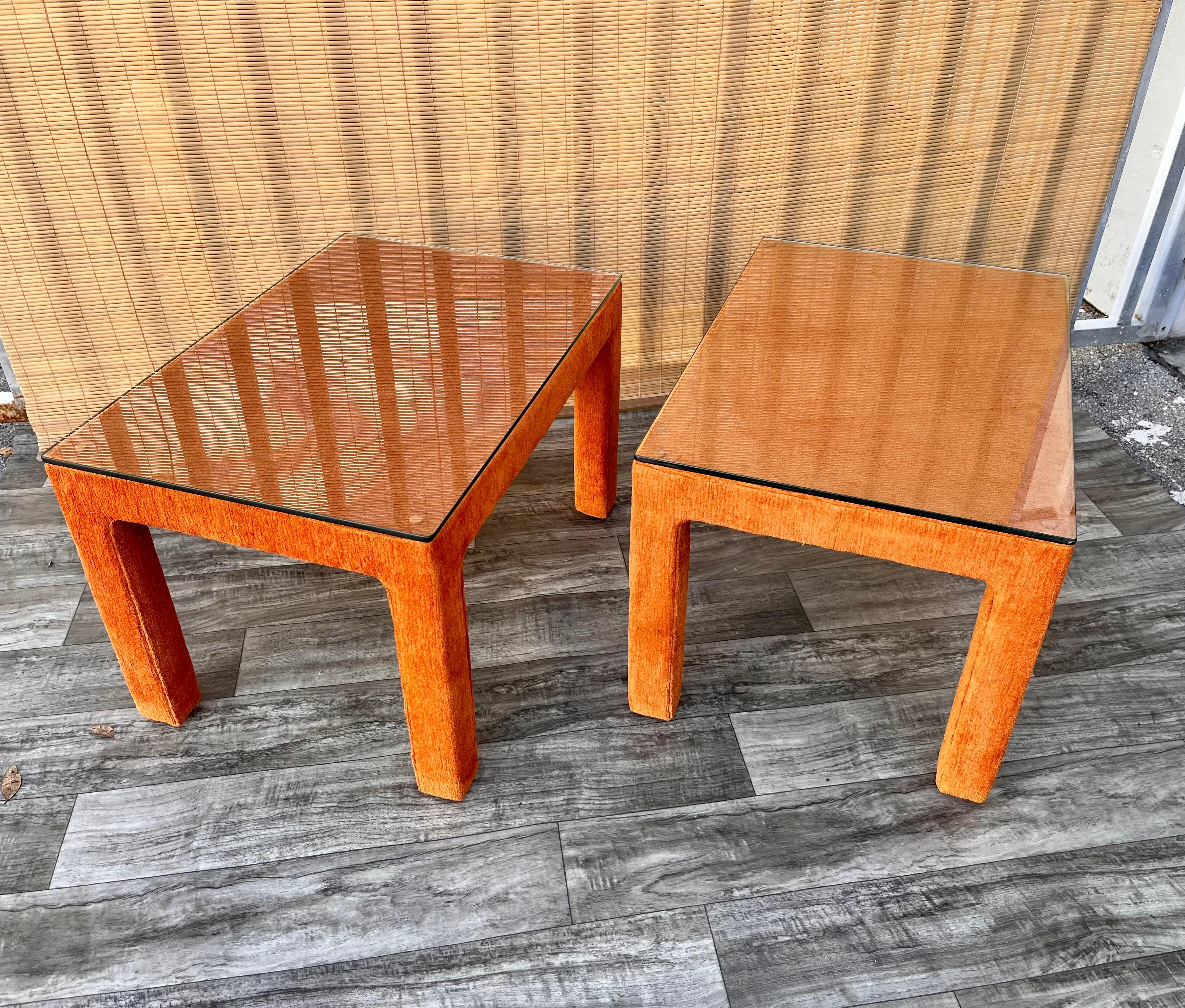A Pair of Vintage Mid-Century Modern Fully Upholstered side tables in the Milo Baughman's Style. Circa 1970s.
Feature a fully upholstered wood frame in a burnt orange velvet with removable glass tops. 
In good original condition with signs of wear