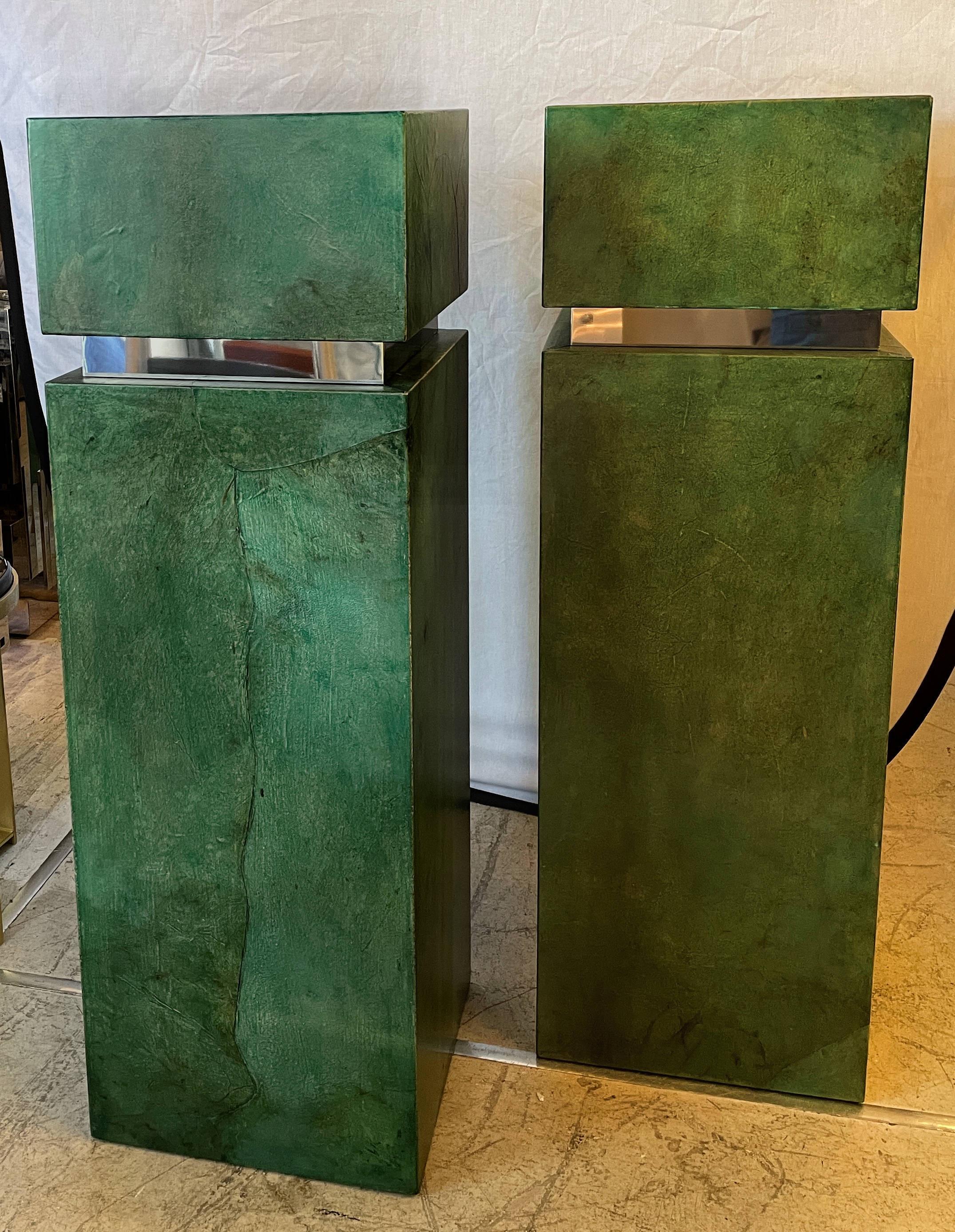 A pair of stunning pedestals with wood bases adorned in lacquered green goatskin parchment and stainless steel, in the style of Aldo Tura. The condition is wonderful and the color is vivid.