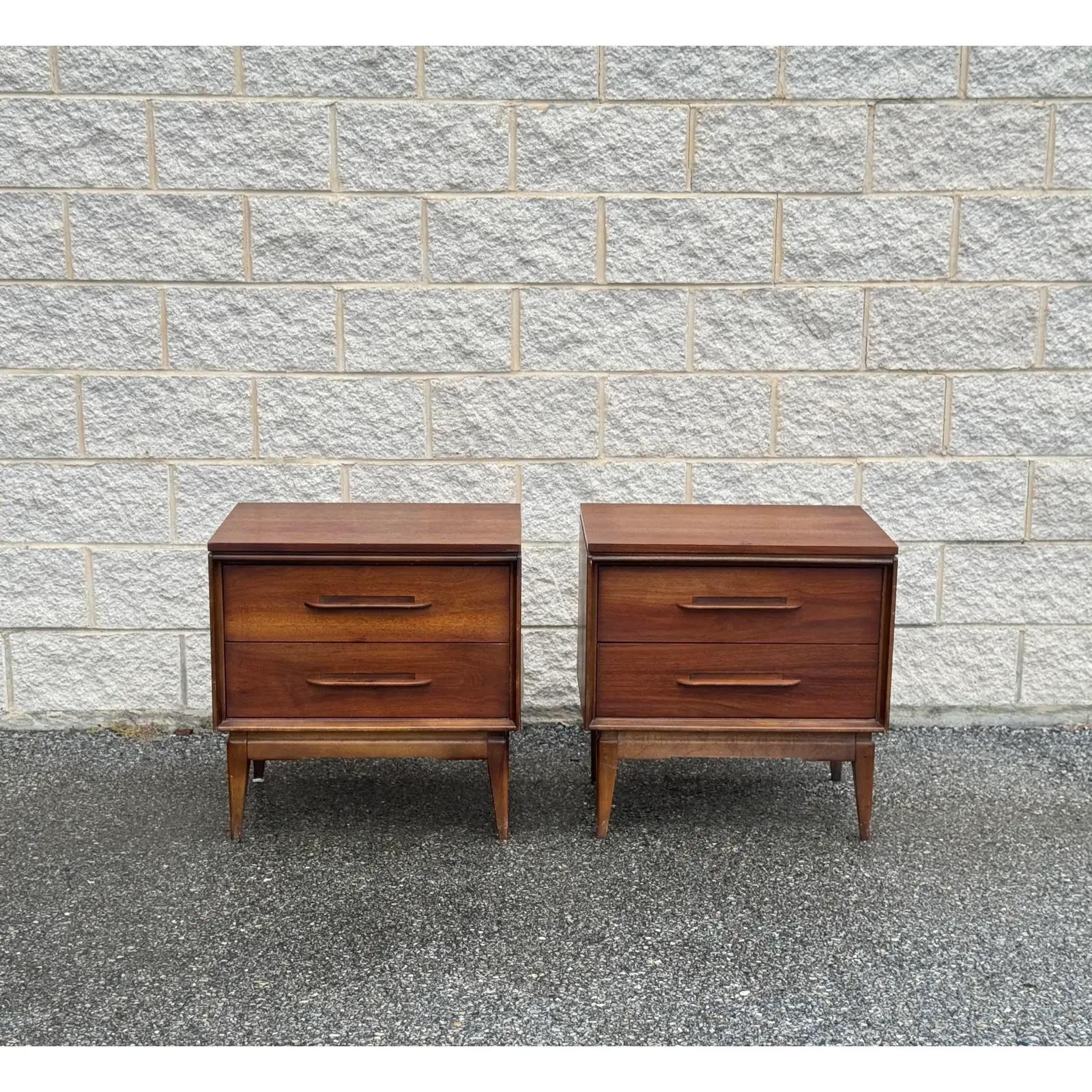 A set of vintage-inspired nightstands featuring elegant walnut wood, tapered legs, and distinctive sculpted handles, crafted by Bassett Furniture.
