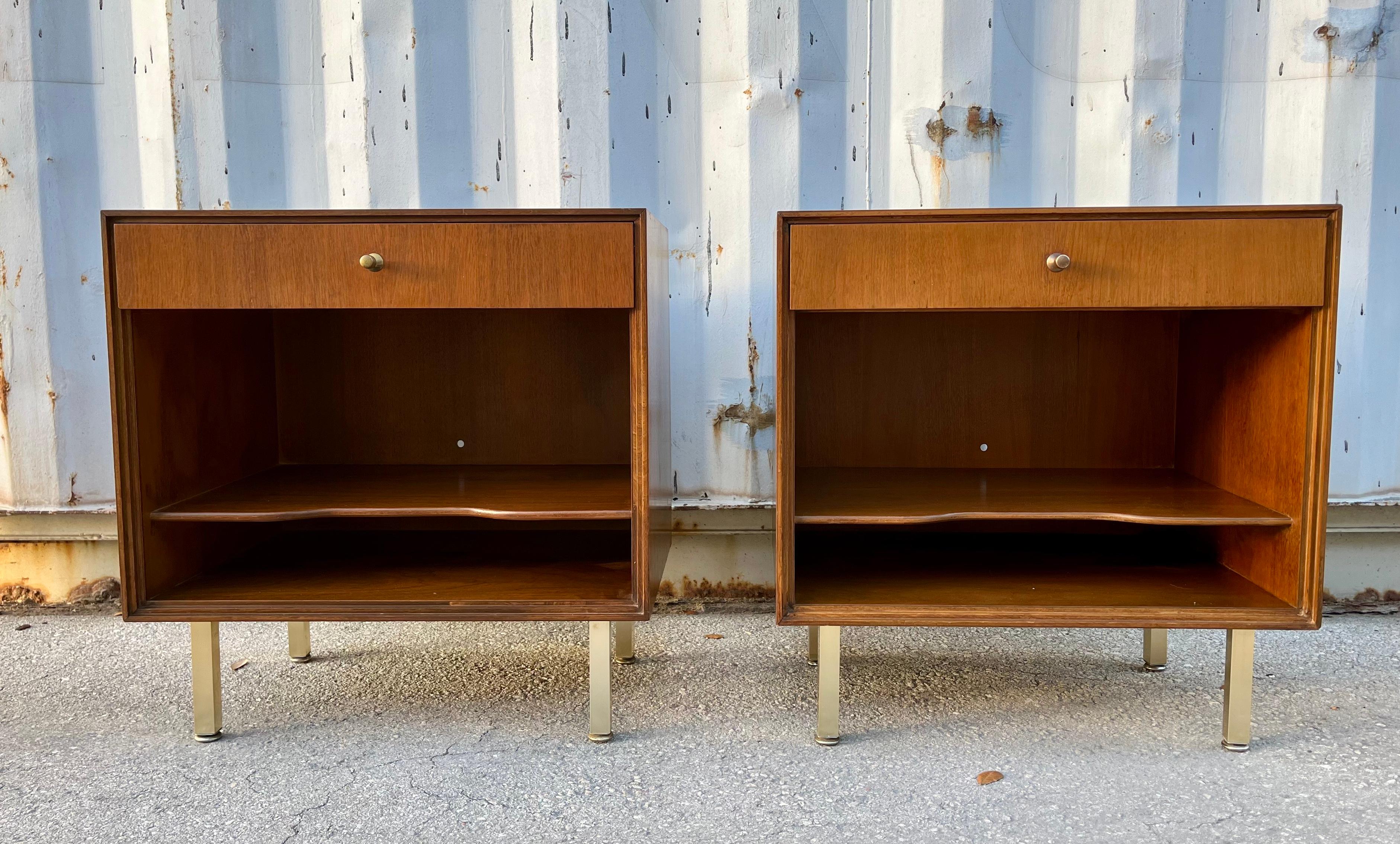 A Pair of Vintage Mid Century Modern Nightstands by John Stuart. Circa 1960s 
Feature a sleek Mid Century Modern Design with anodized legs, one drawer with brass hardware, and one shelf for extra storage.
In good original condition with sigsn of