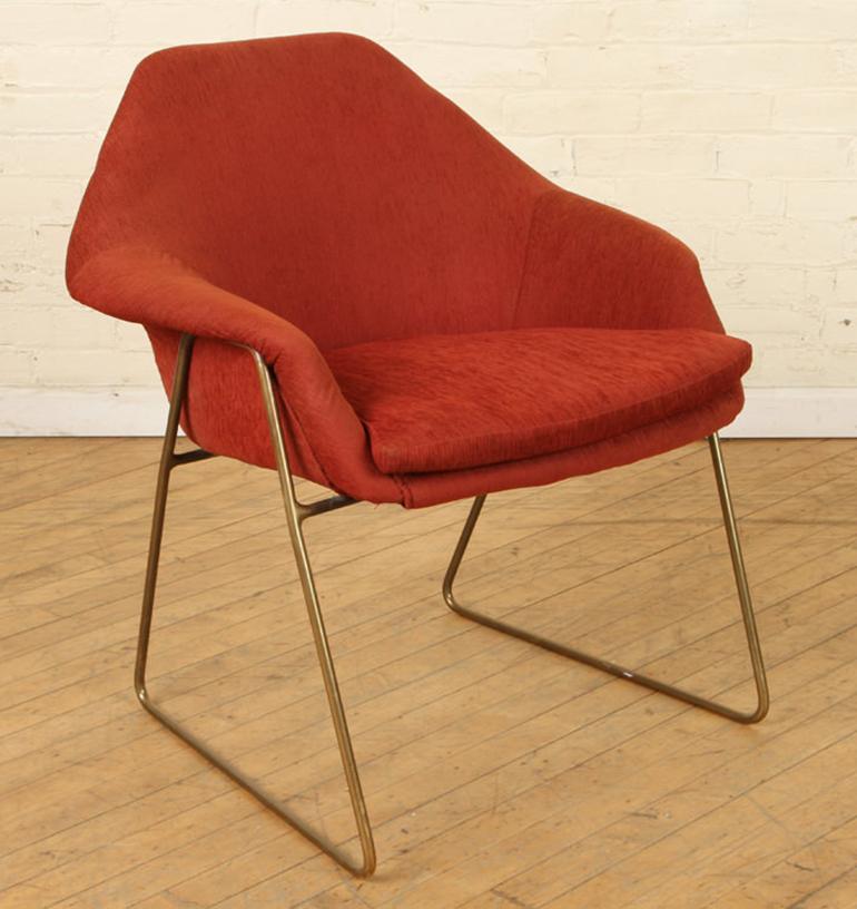 A pair of Mid-Century Modern sculpted upholstered armchairs raised on bronze legs. Upholstered in a rich deep orange weave, the chairs are comfortable while space efficient.