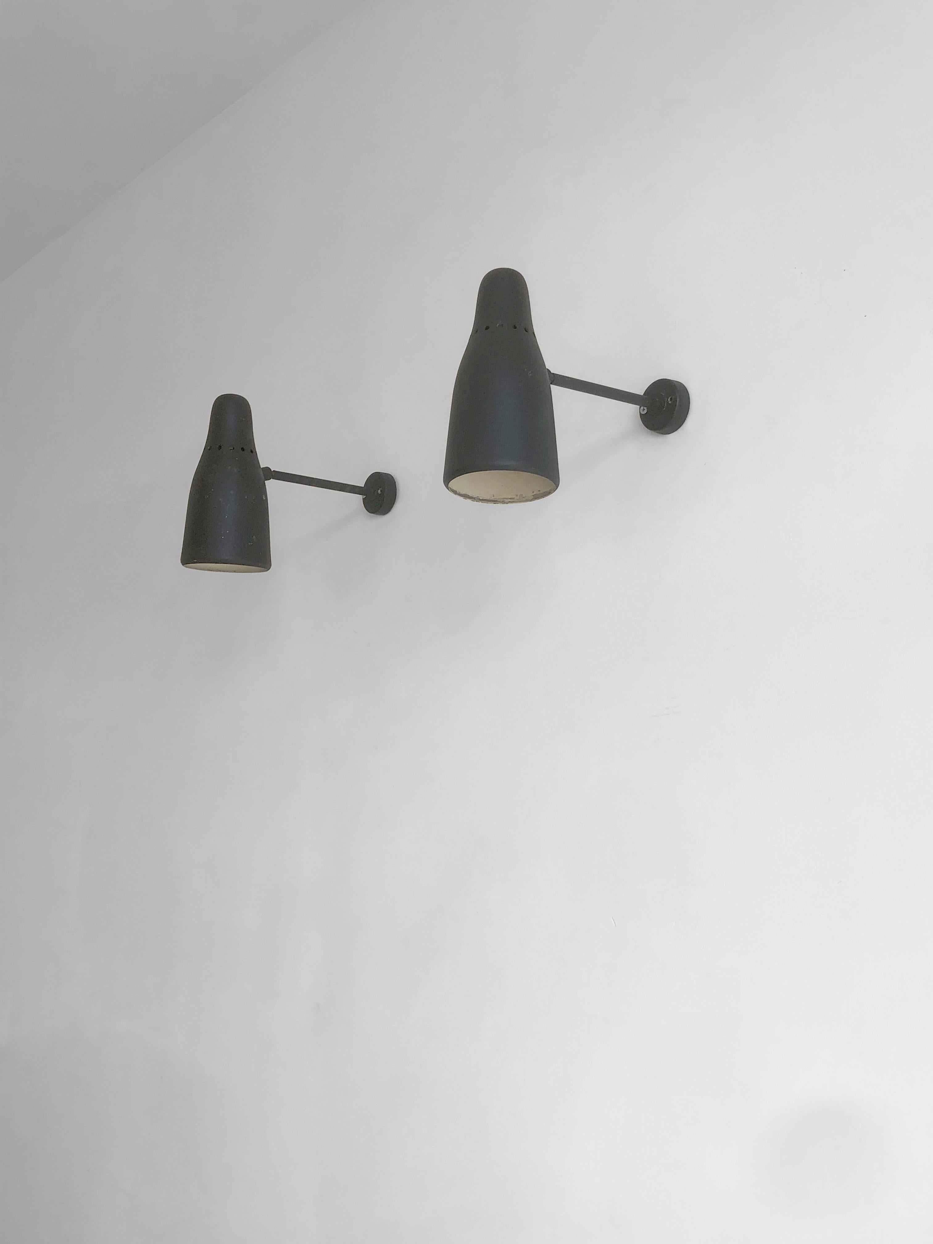 A beautiful and highly decorative pair of Mid-Century-Modern orientable wall sconces, attributed to Pierre Guariche, France, 1950.

These appliques are mounted on a circular black laquered wall base, a short horizontal arm, and a beautiful