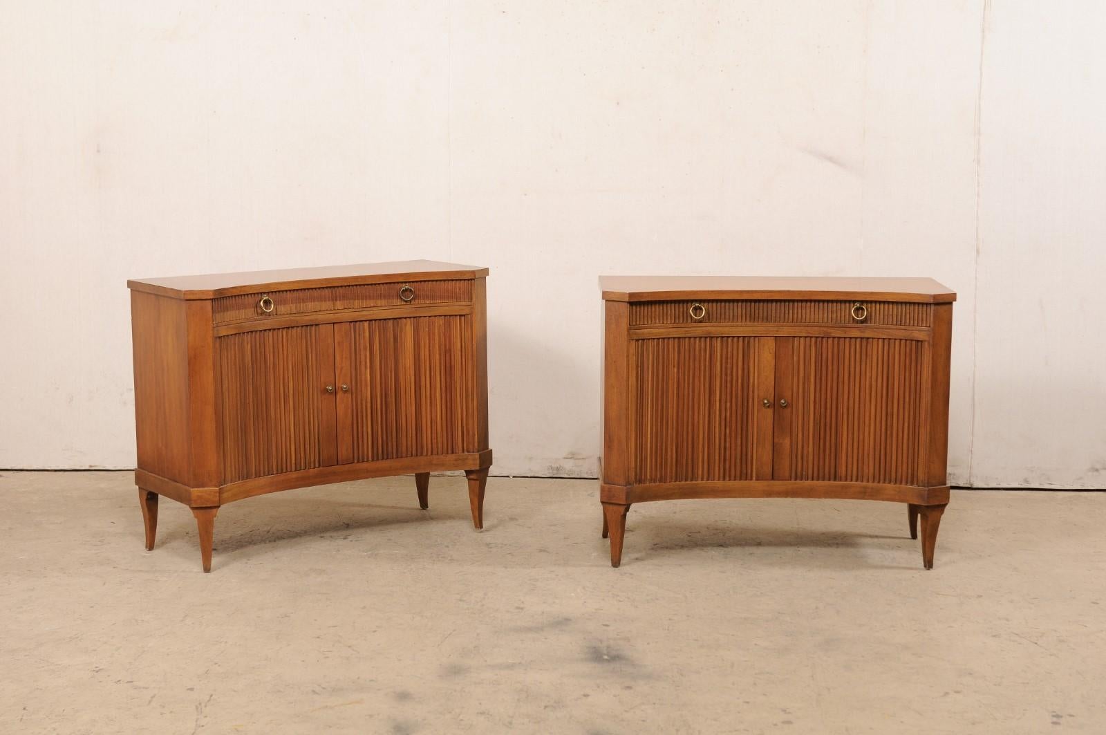 A pair of curved-front wooden chests, with single drawer and tambour doors, from the mid 20th century. These vintage chests from American furniture makers, 