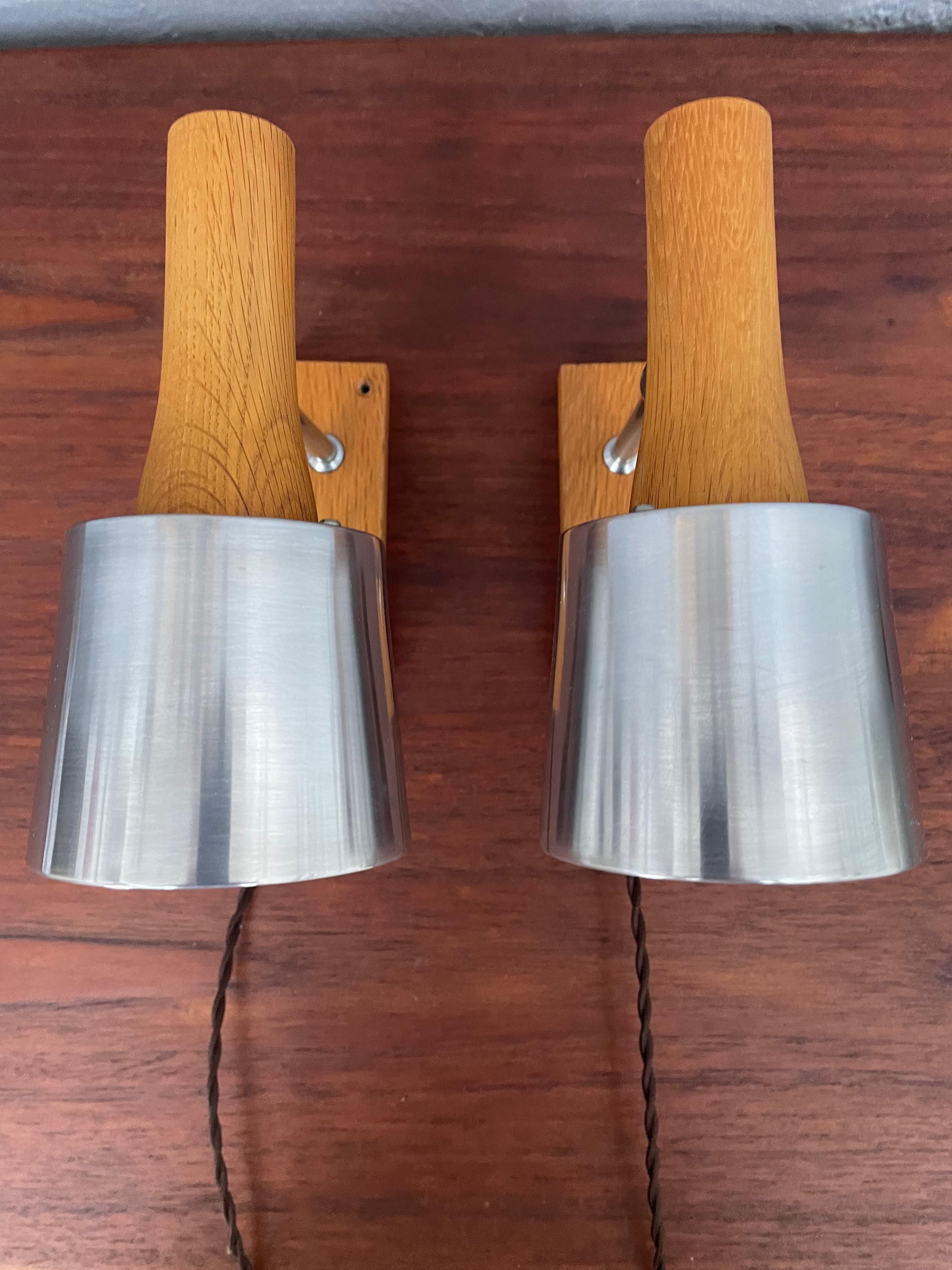 Una coppia di lampade da parete classiche della metà del secolo scorso, realizzate dalla danese Lyfa. 
Le lampade sono costituite da un paralume in alluminio lucidato e dipinto di bianco all'interno. 
Porta lampadine E27 originali in bachelite. 
Il
