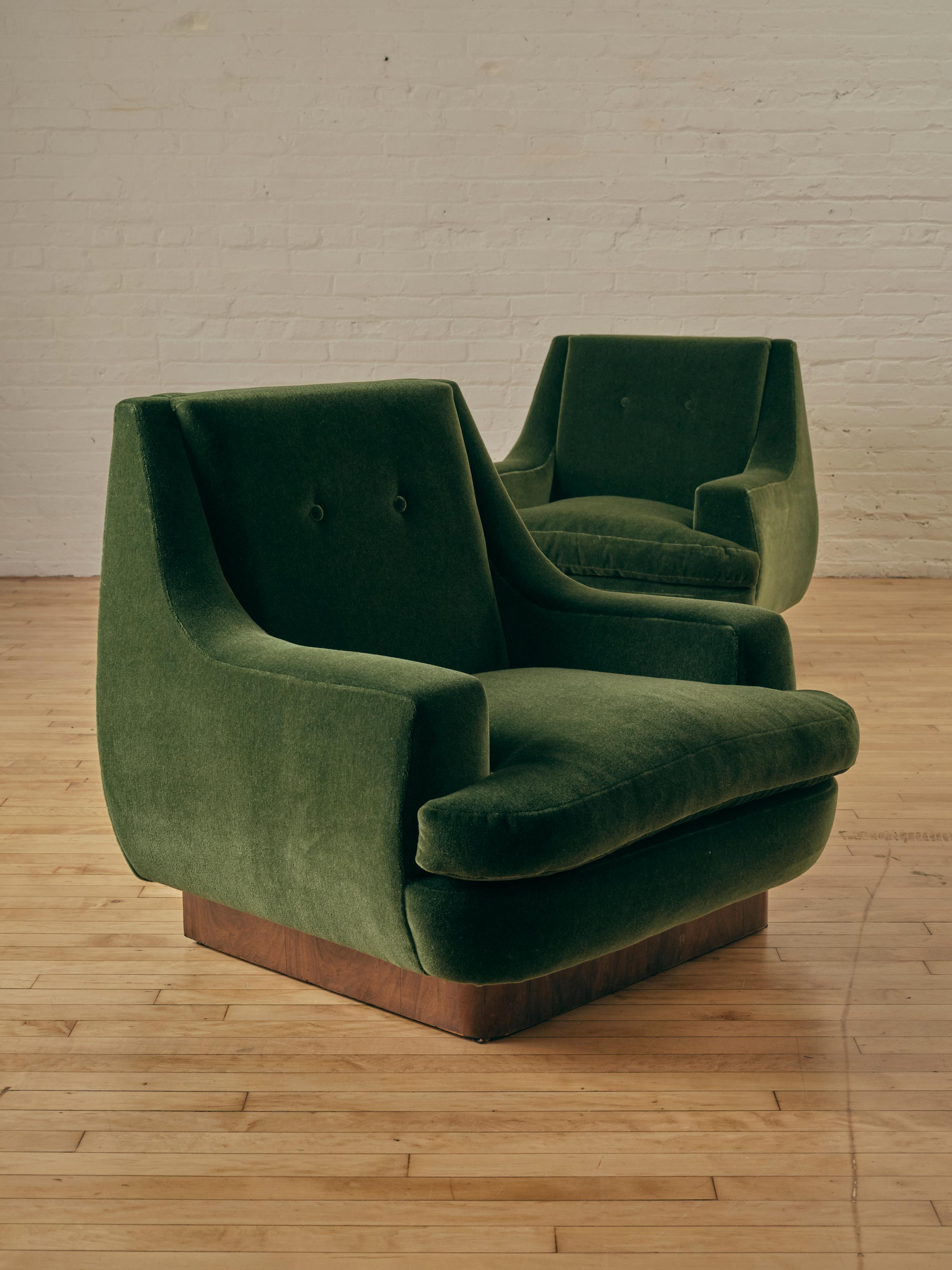 A Pair of Modernist Cube Lounge Chairs reupholstered in Dedar Milano's Vladimiro Mohair in color 25, Verde Bottiglia, sitting atop a rich wooden base. 

