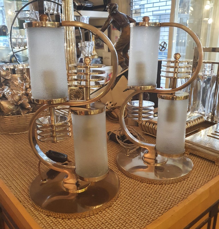 A pair of important nickel-plated Modernist table lamps by Edgar Brandt (French, 1880-1960), each featuring an ‘S’ shaped body on a circular base, with two opaque, deeply-etched glass cylinder shades, and circular disk and ball motifs. Each lamp