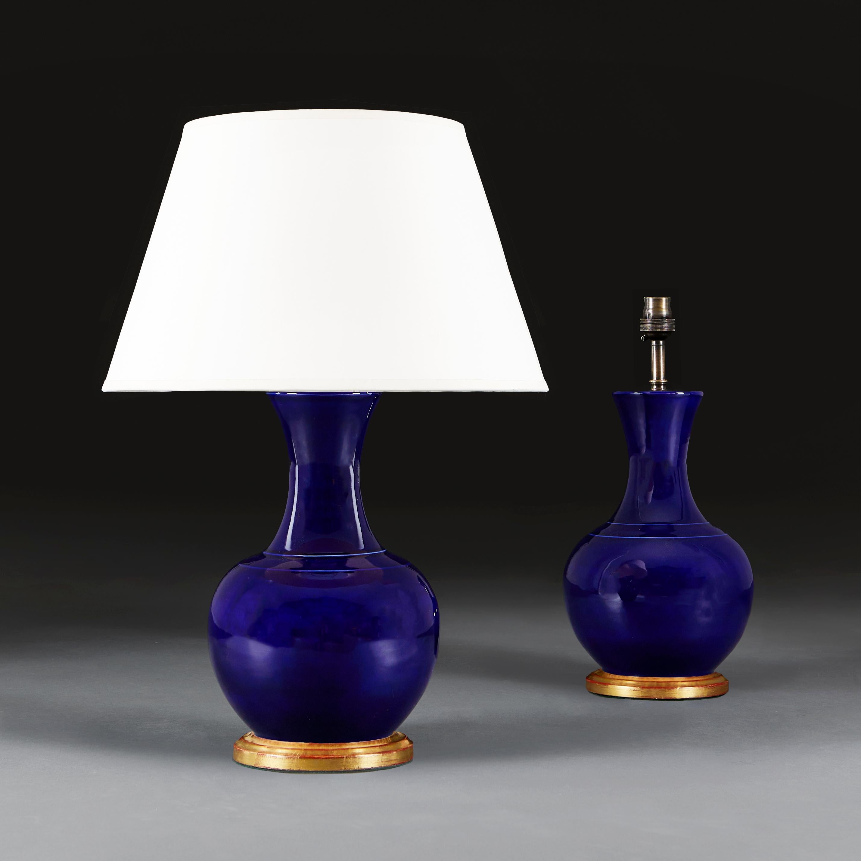Paire de vases chinois du vingtième siècle en glaçure bleu foncé, avec des cols évasés, maintenant montés comme lampes avec des bases tournées en bois doré.

Hauteur du vase             36.00cm
Hauteur avec abat-jour      61.00cm
Diamètre du corps  