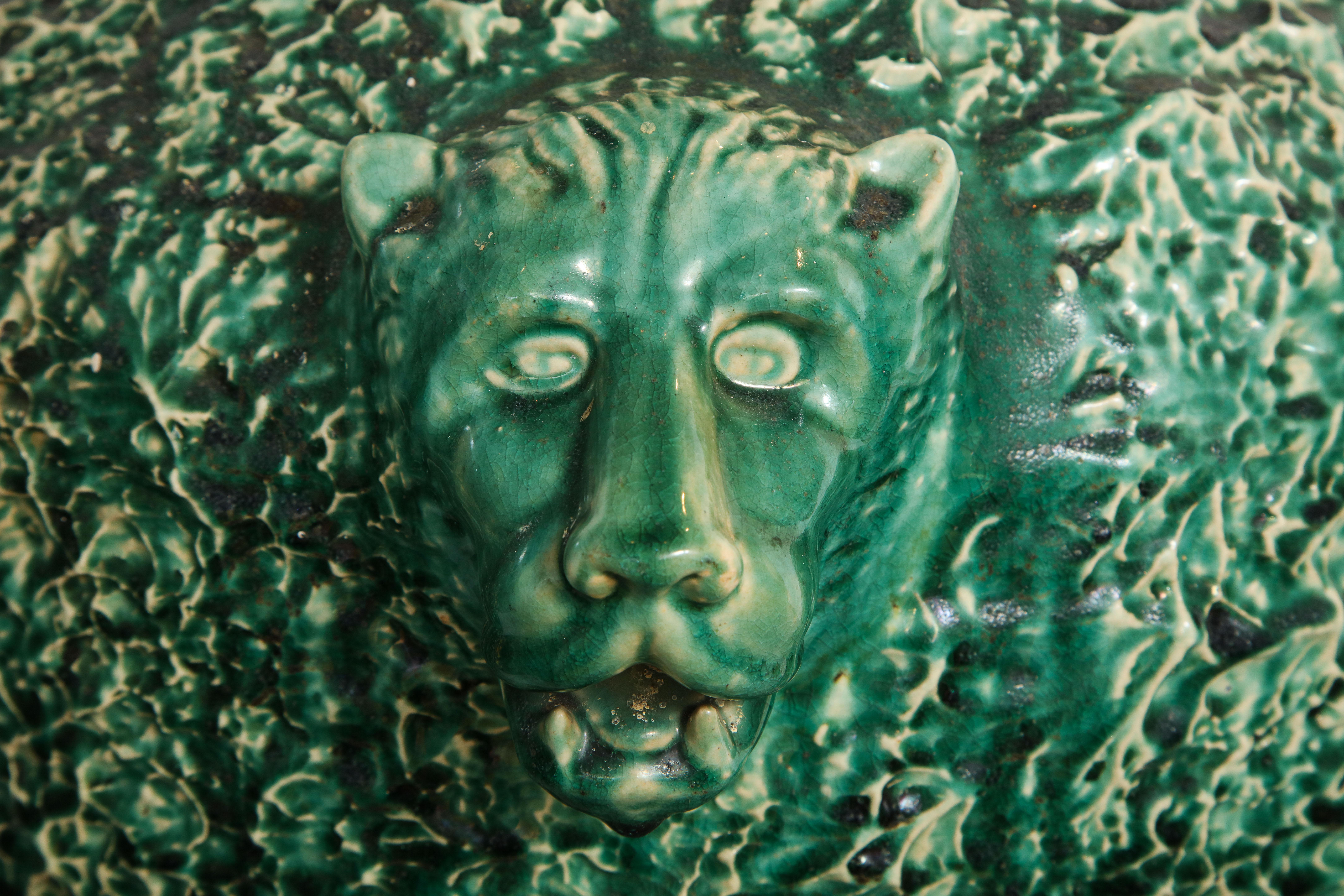 Each green ceramic urn with a hand decorated surface and flanked by the face of a lion. Probably Ohio.
 