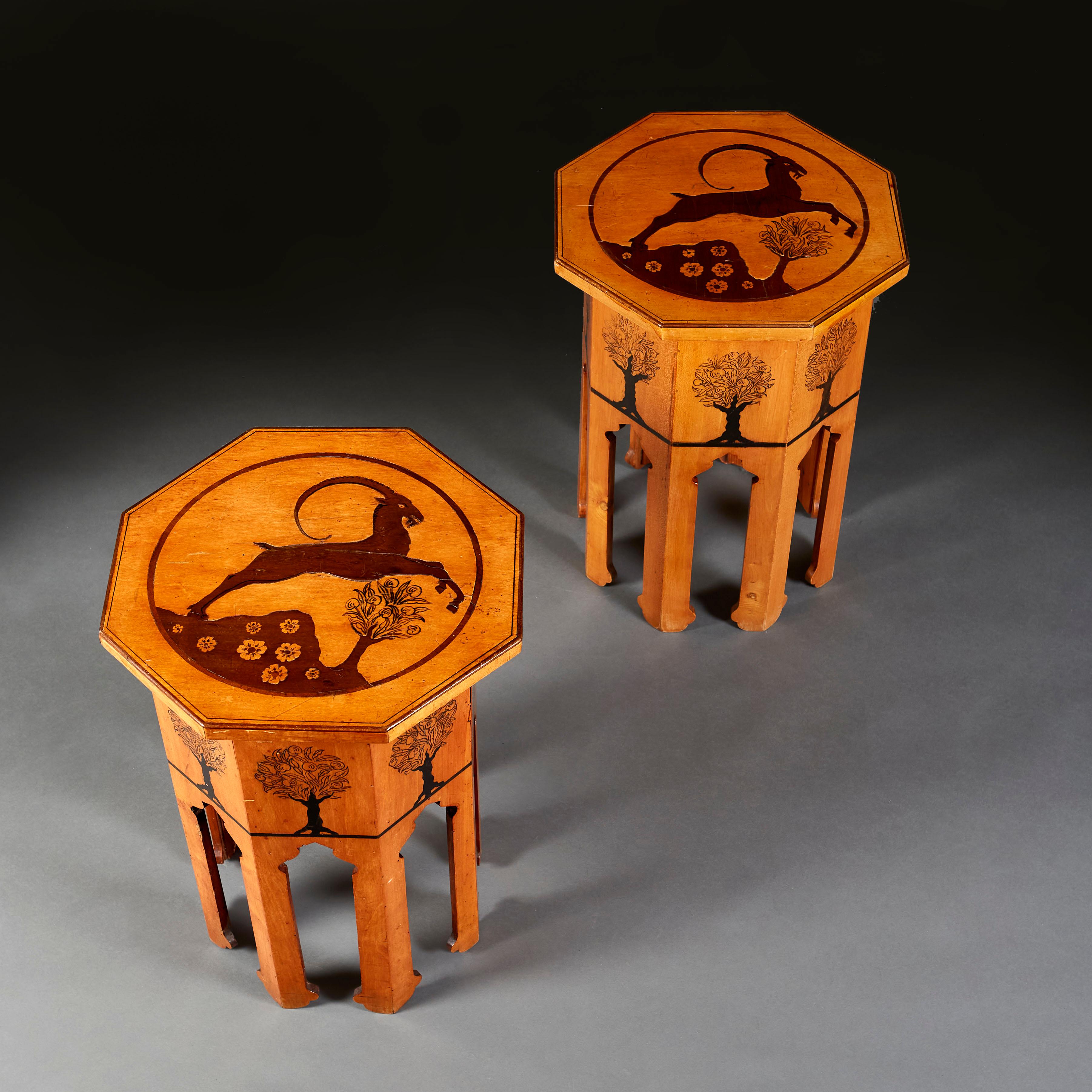 A pair of early twentieth century Moorish occasional tables of octagonal form, the tops with leaping antelope and stylised trees, the bases with arched panels.