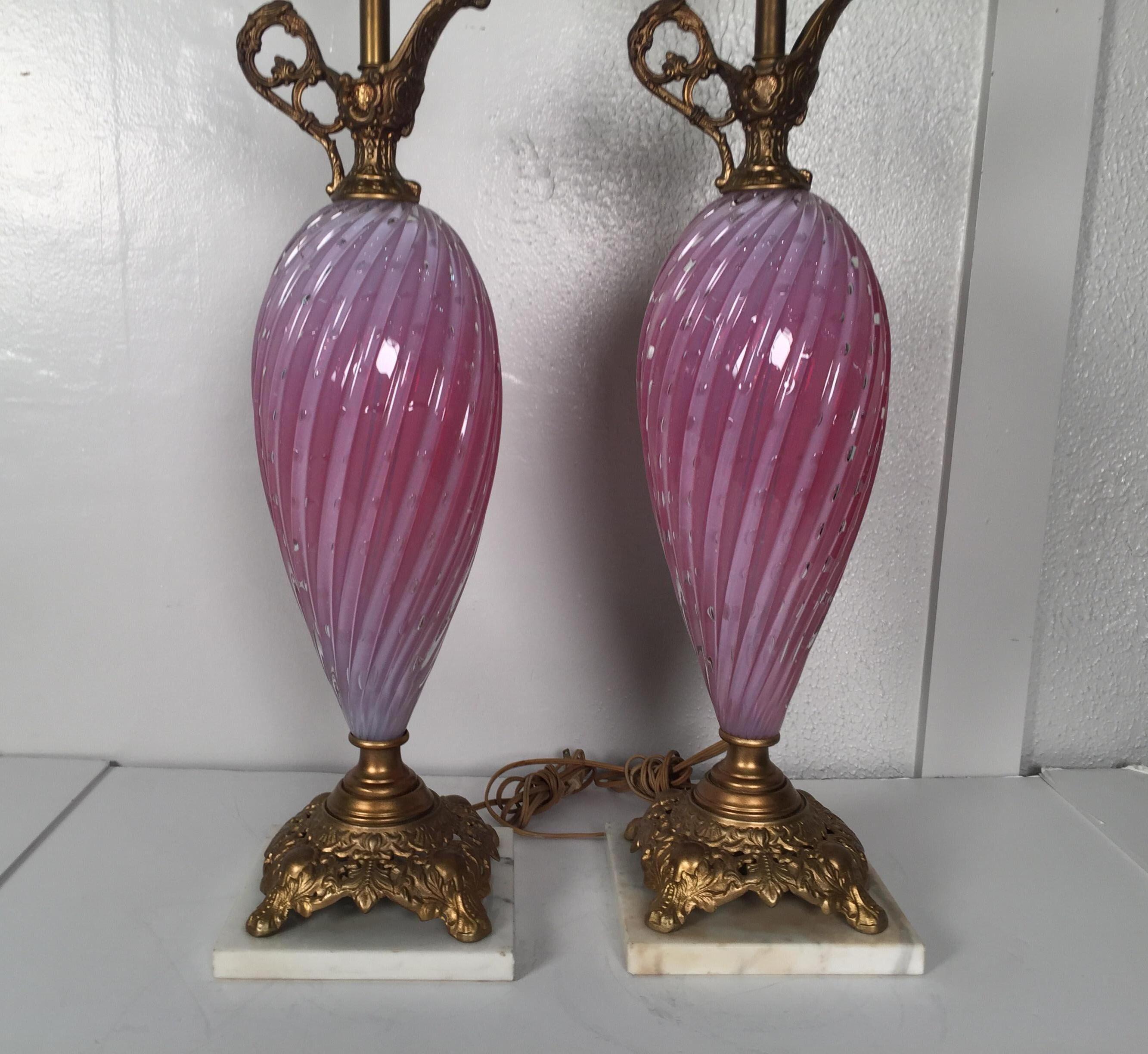 A pair of Rose and white Murano glass ewer form lamps. The glass bodies with gilt grass top and base. The height with an appropriate shade is 39 to the top of the finial. The base is 7.5 inches square. 29 inches to the top of the socket.