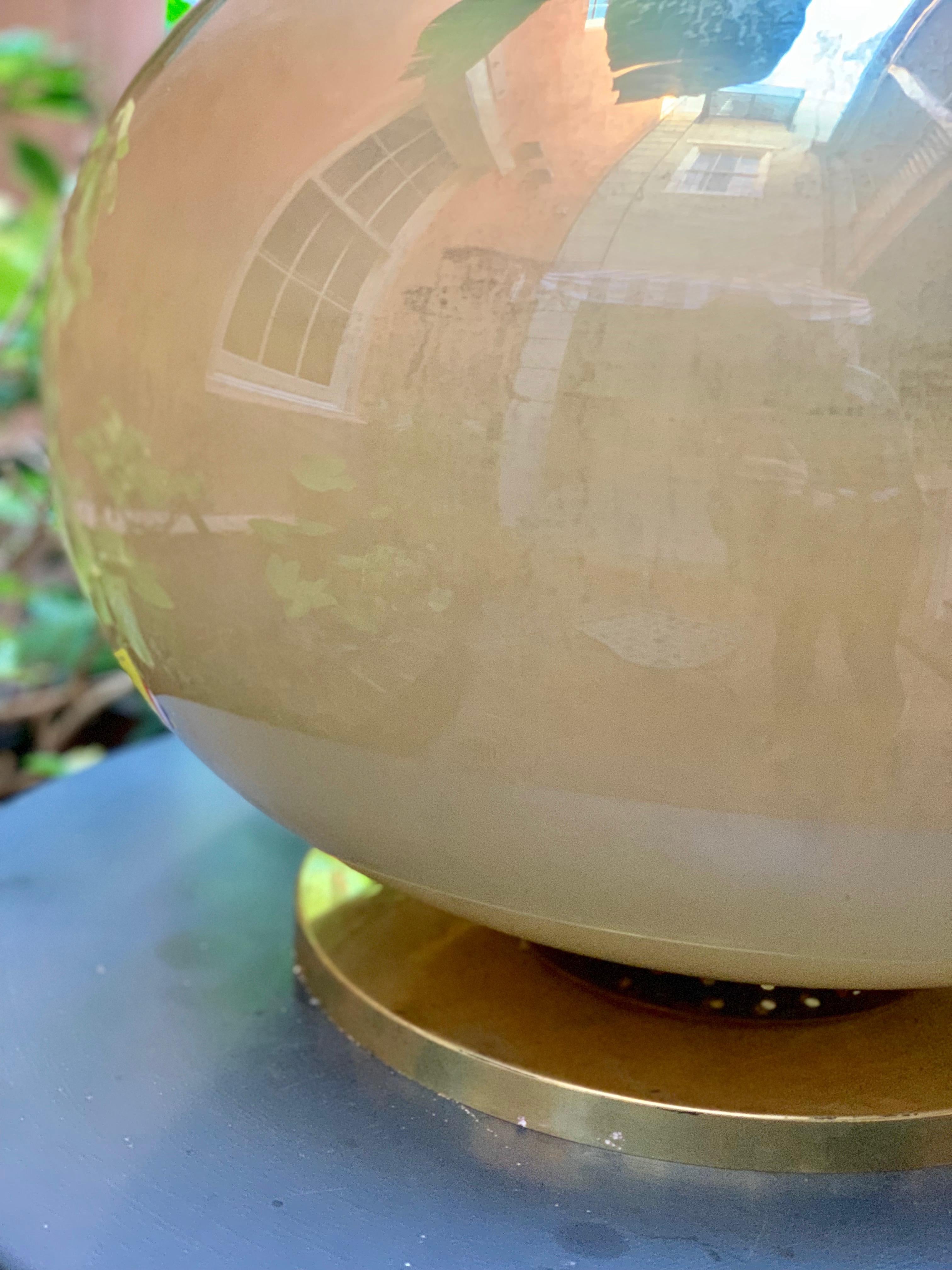 A pair of blown Murano glass globe lamps set on brass bases circa 1950 in the Mid-Century Modern style. The interiors are sprayed with a golden pigment, creating an ethereal glow.

Each lamp takes three small tapered bulbs.