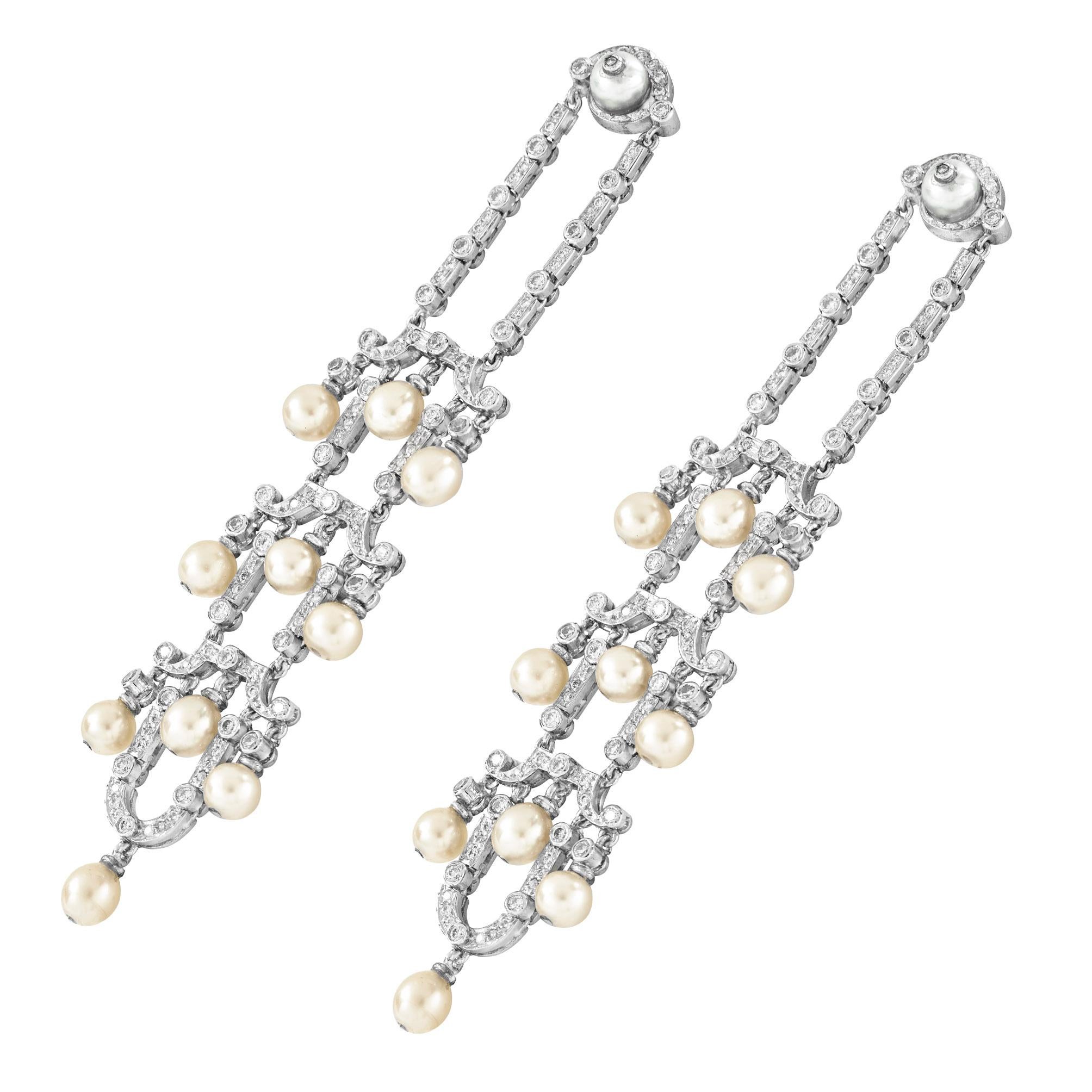 A pair of natural pearl and diamond drop earrings, each earring comprising of three sets of diamond-set tiers, each with three pearl drops and the last terminated with one pearl drop, suspended from a pearl with a diamond to the centre surrounded by