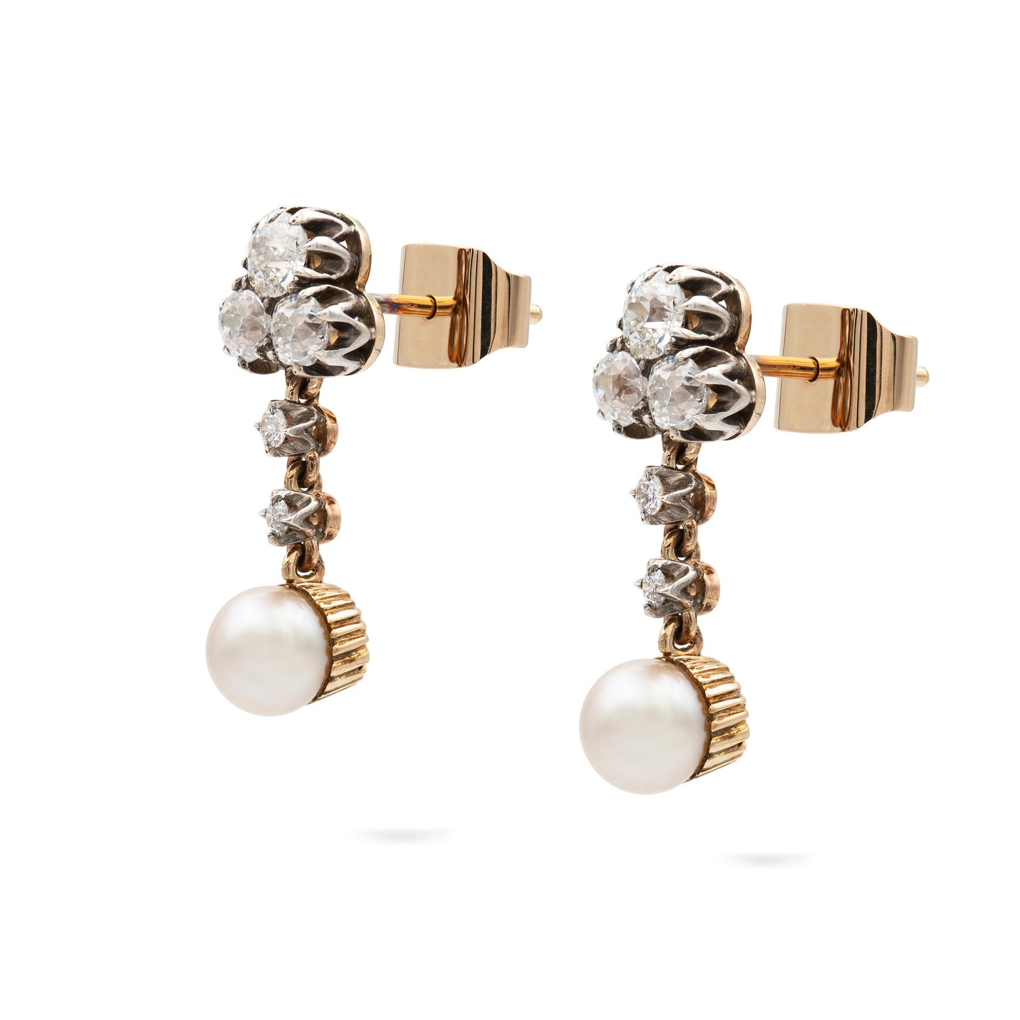 A pair of natural pearl and diamond drop earrings, the pearl set in a fluted gold cup accompanied by GCS certificate stating natural saltwater, suspended from a line of two diamonds with three old-cut diamonds set in a trefoil design to the top,