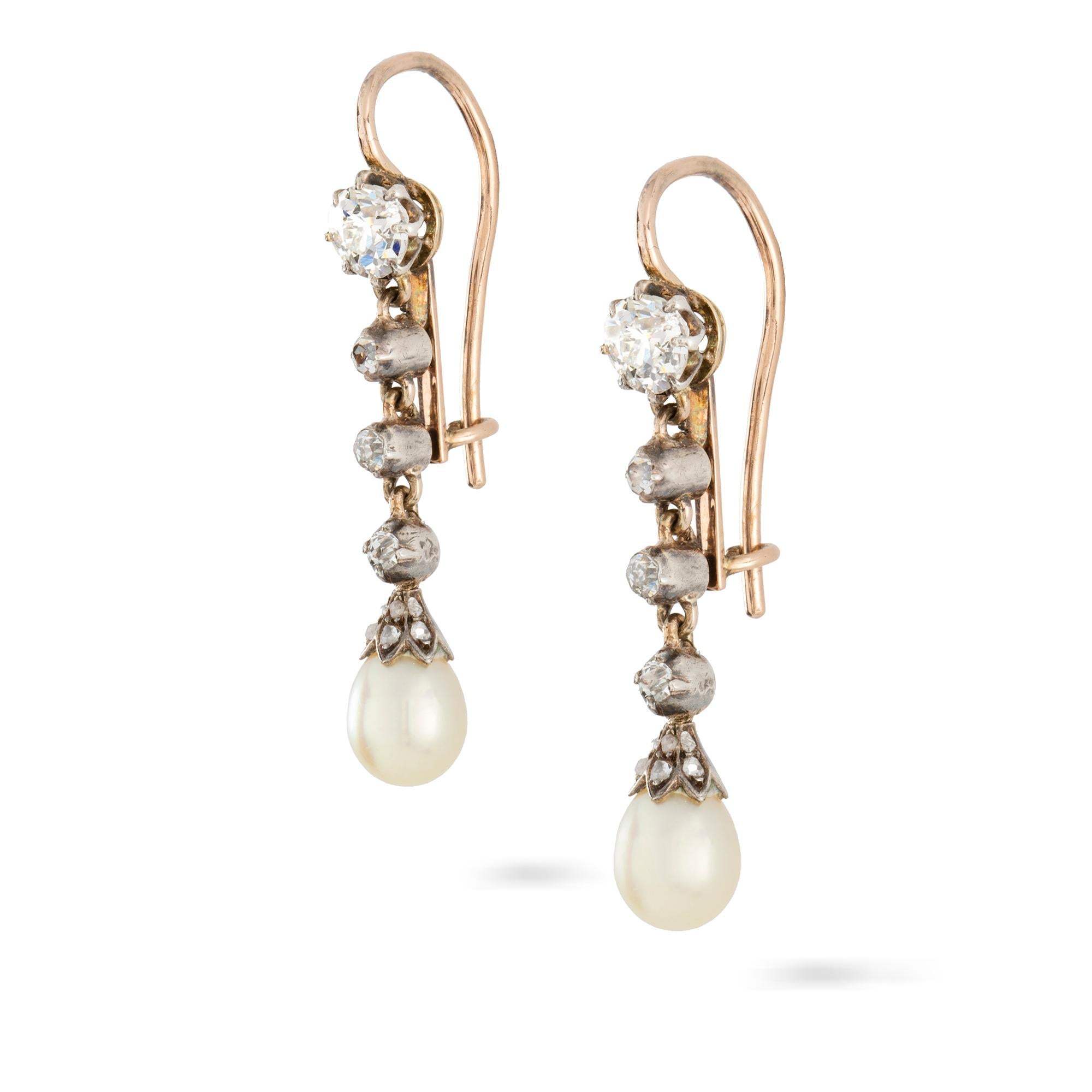 A pair of early 20th century natural pearl and diamond drop earrings, each consisting of an old-cut diamond top suspending a line of three old-cut diamond collets to a natural pearl drop terminal with diamond-set cap, all set to a silver front and