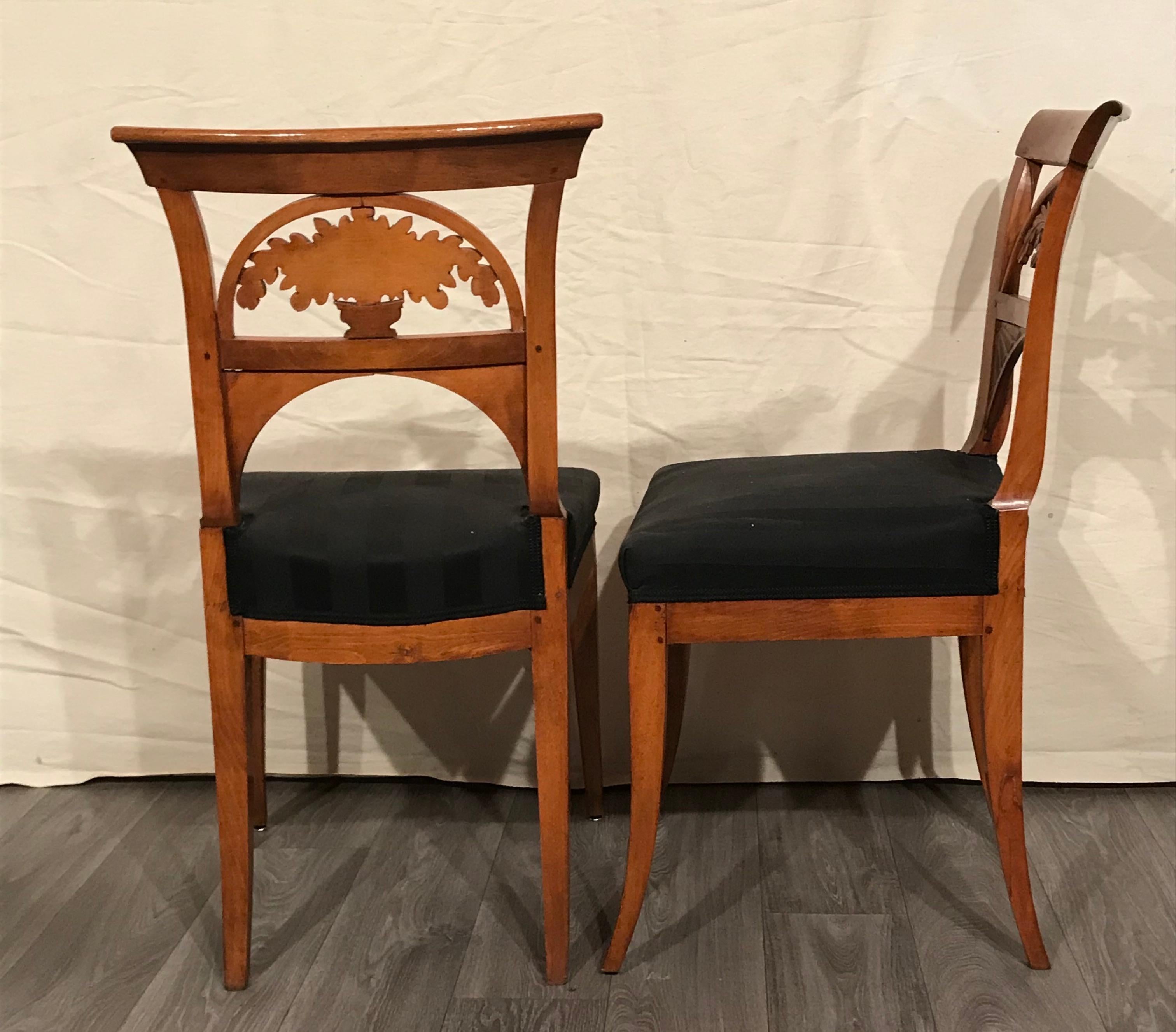 This pair of Neoclassical chairs has very special backrests. The openwork decorations feature naturalistically hand carved oak branches. 
The chairs are in very good condition. The wood has been refinished, the upholstery is in good condition. 
The