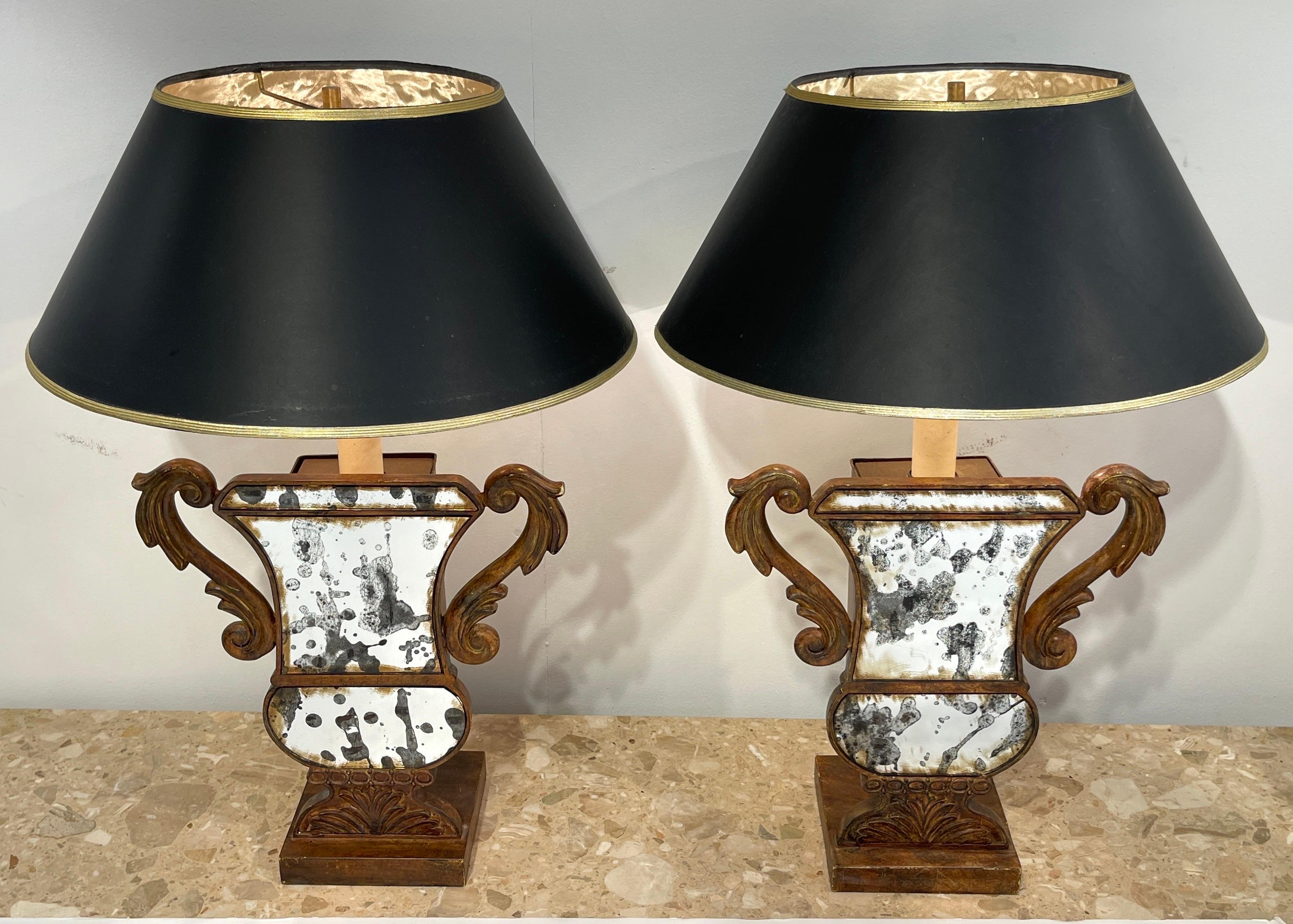 A Pair of Neoclassical Tole & Eglomise Mirrored Urn Motif Lamps 
Later 20th Century 

Each one eglomise mirrored twin handled urn, raised on a square pedestal base
Rewired ready to place.
Shown with display shades 8-Inches high x 17-inch