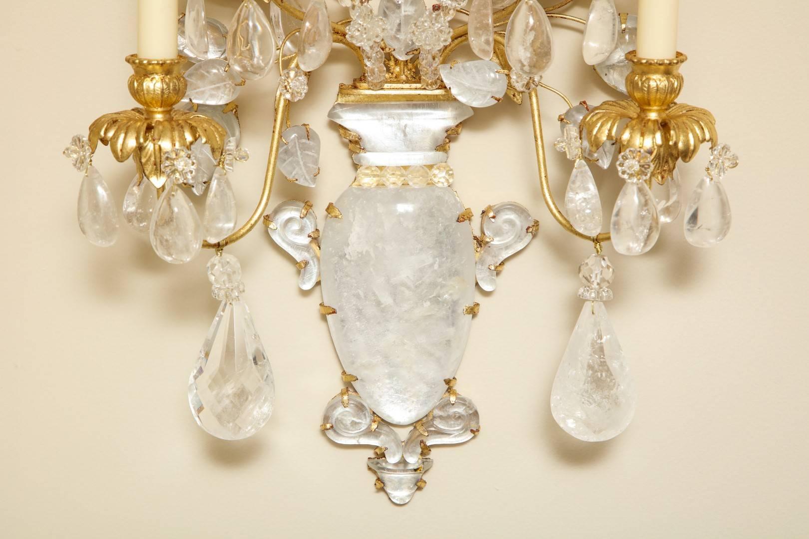 A pair of new four-light rock crystal sconces with gilt-metal frames, the vase-shaped back plates with etching motif and gadrooning, issuing gilt-metal branches of rock crystal leaves and flowers formed with rock crystal drops, the bobeches also