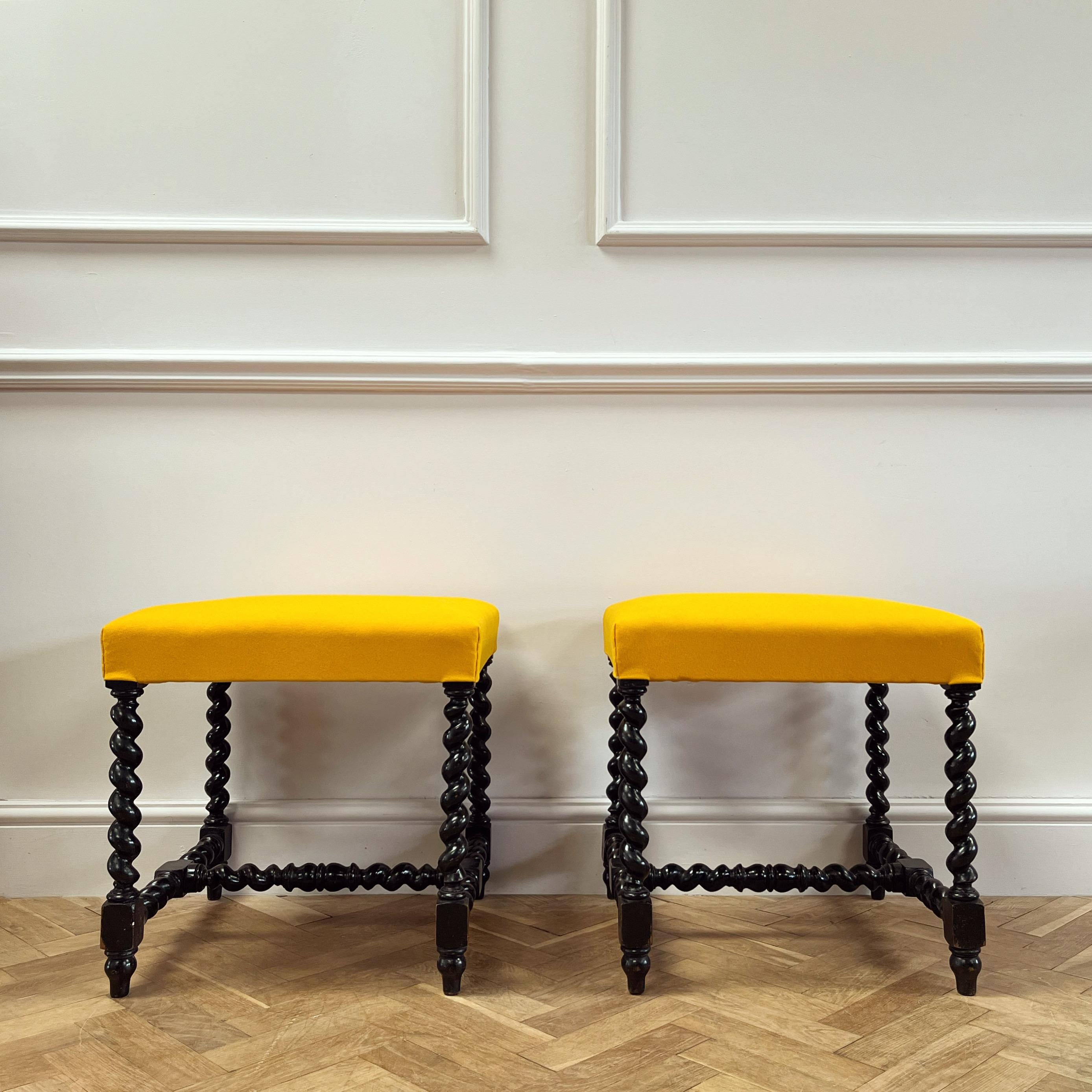 Une paire de tabourets carrés ébonisés avec des supports et une structure en spirale, recouverts d'un tissu de laine de cérémonie britannique. 

Anglais, fin du XIXe siècle