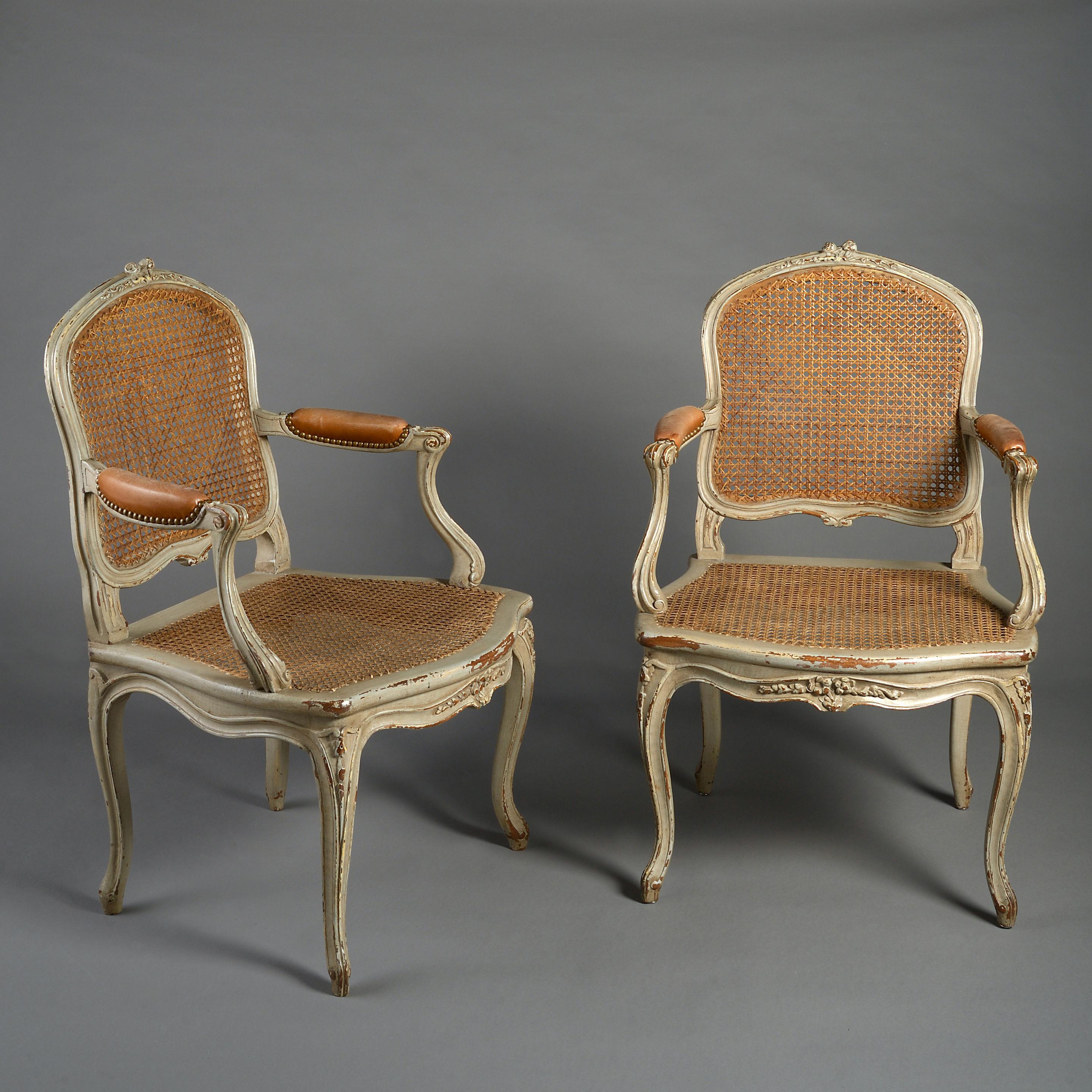 A pair of late 19th century painted fauteuil in the Luis XV manner having cartouche backs, scrolling arms, shaped seats, alternating On cabriole legs, having cane work throughout. Now with drop-in squab seats.