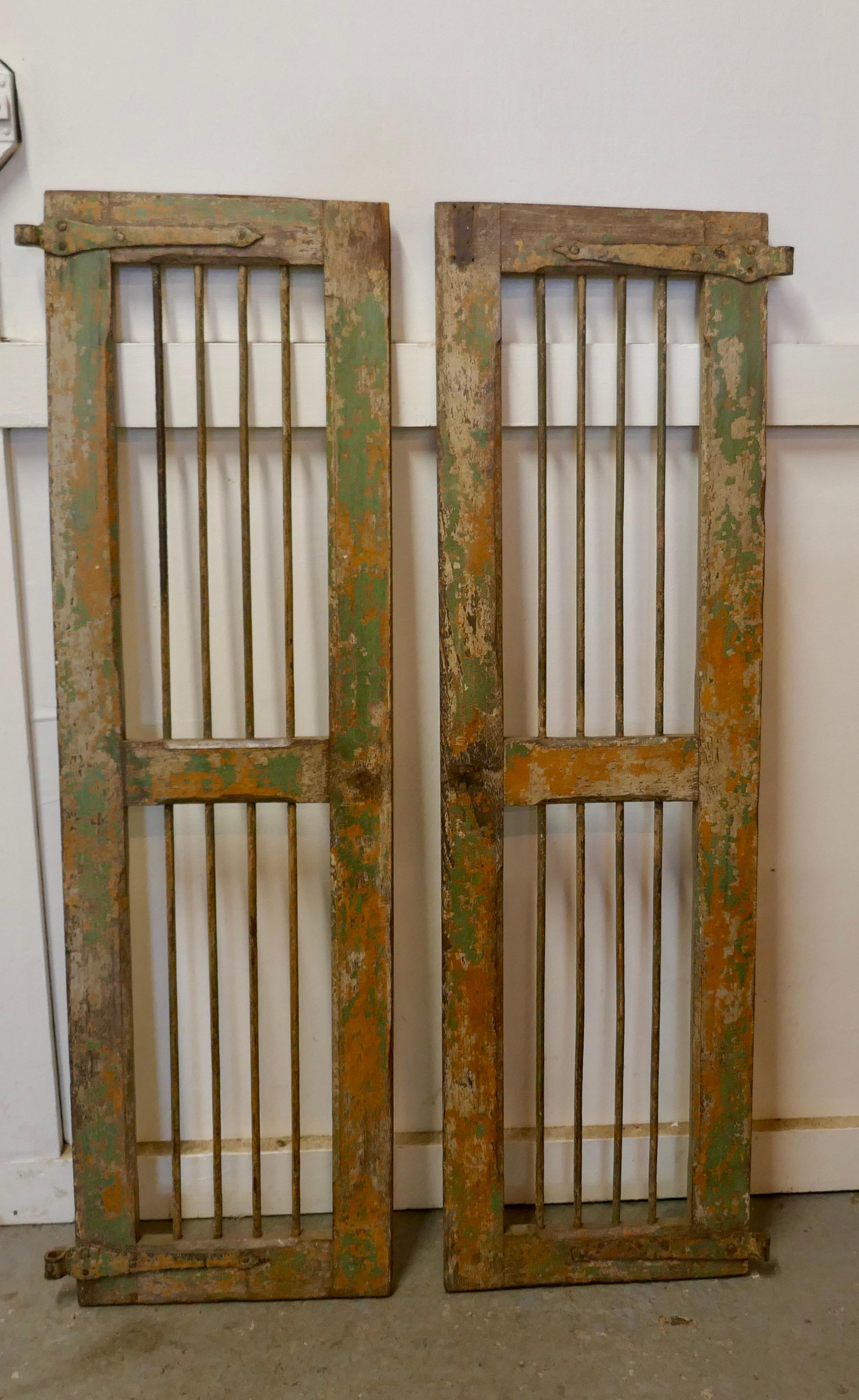 A Pair of North African Wood and Iron Window Shutters

These are decorative fruitwood shutters with Iron Rod insets, they have naturally distressed paint this is worn and shabby showing the original colours of Orange and Green, they are set with