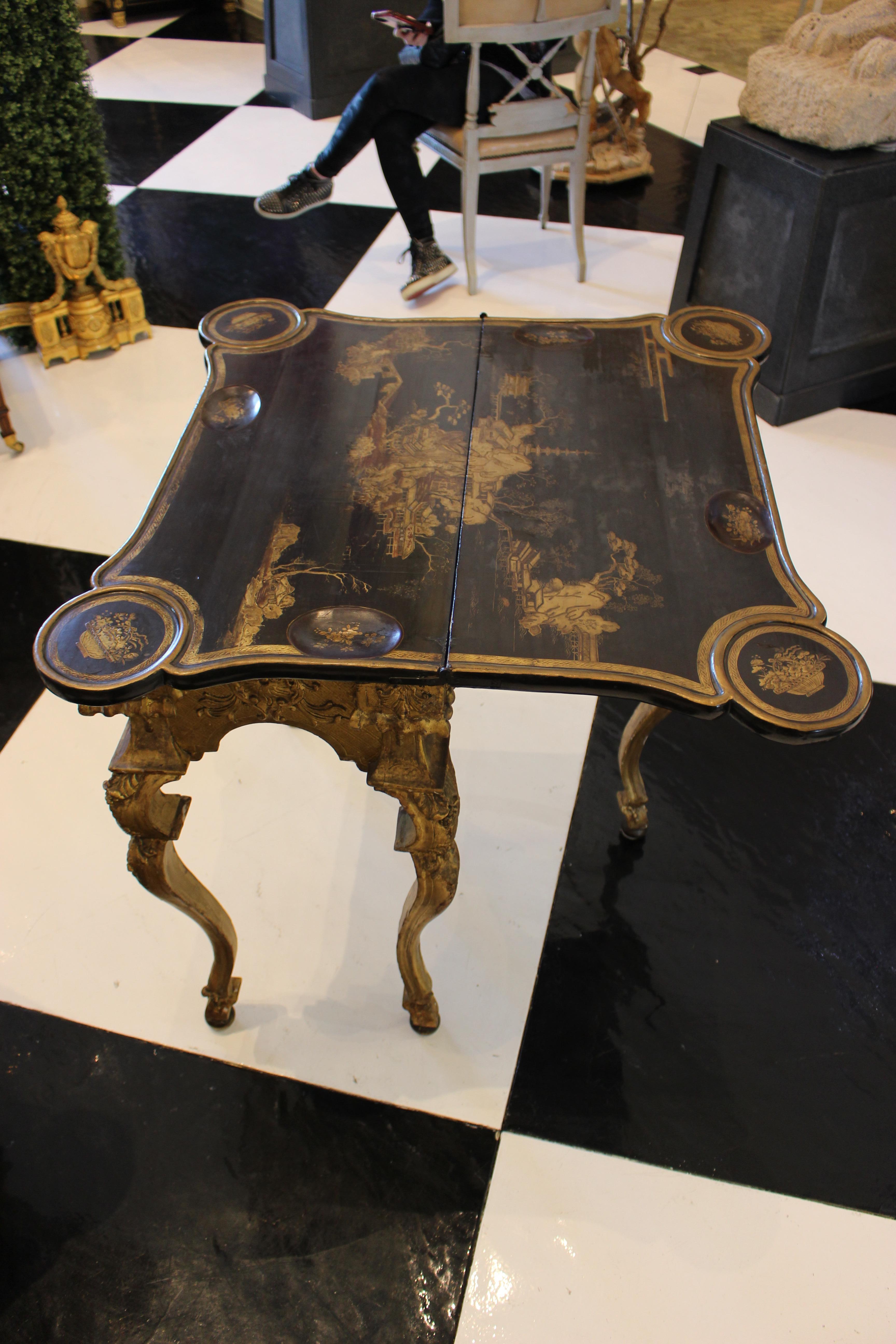 A pair of North European giltwood and gilt composition game tables with Chinese lacquer tops.
