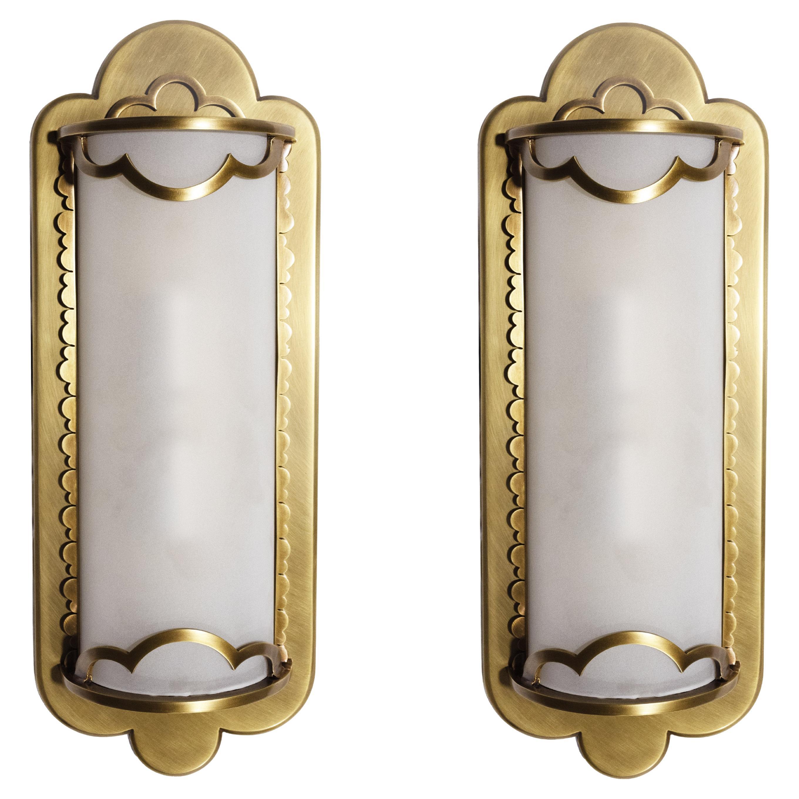 A pair of brass sconces with stylized cloud motifs. The scalloped border securing a curved frosted glass covers concealing two candelabra sockets. Designed by David Duncan Studio, can be made in custom sizers and finishes.