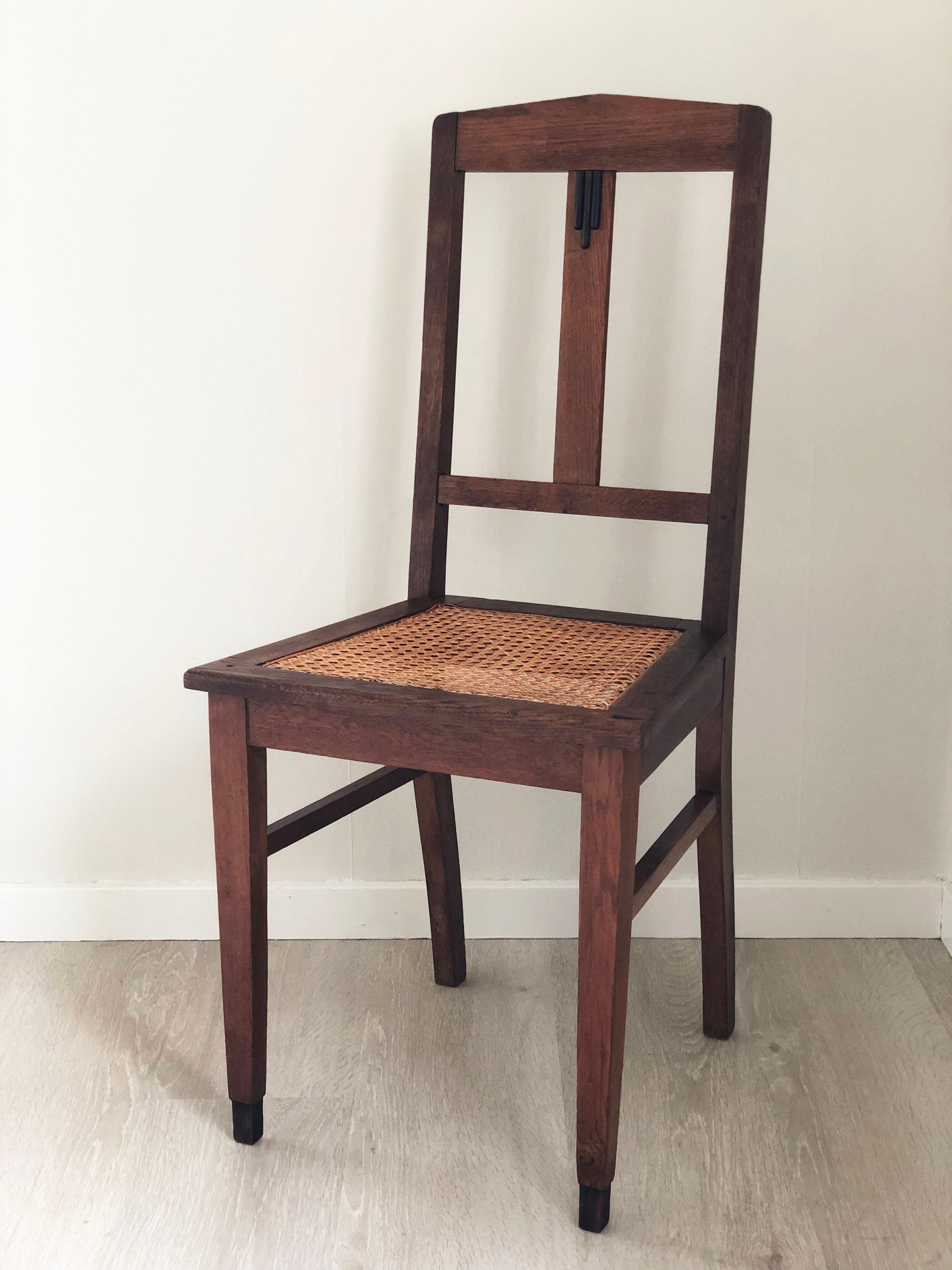 Este par de sillas de comedor Art Decó hechas a medida, fabricadas en Holanda en la década de 1920, muestran el estilo atrevido y escultural del movimiento de la Escuela de Ámsterdam. Hechas de roble macizo, cada silla tiene un asiento de caña