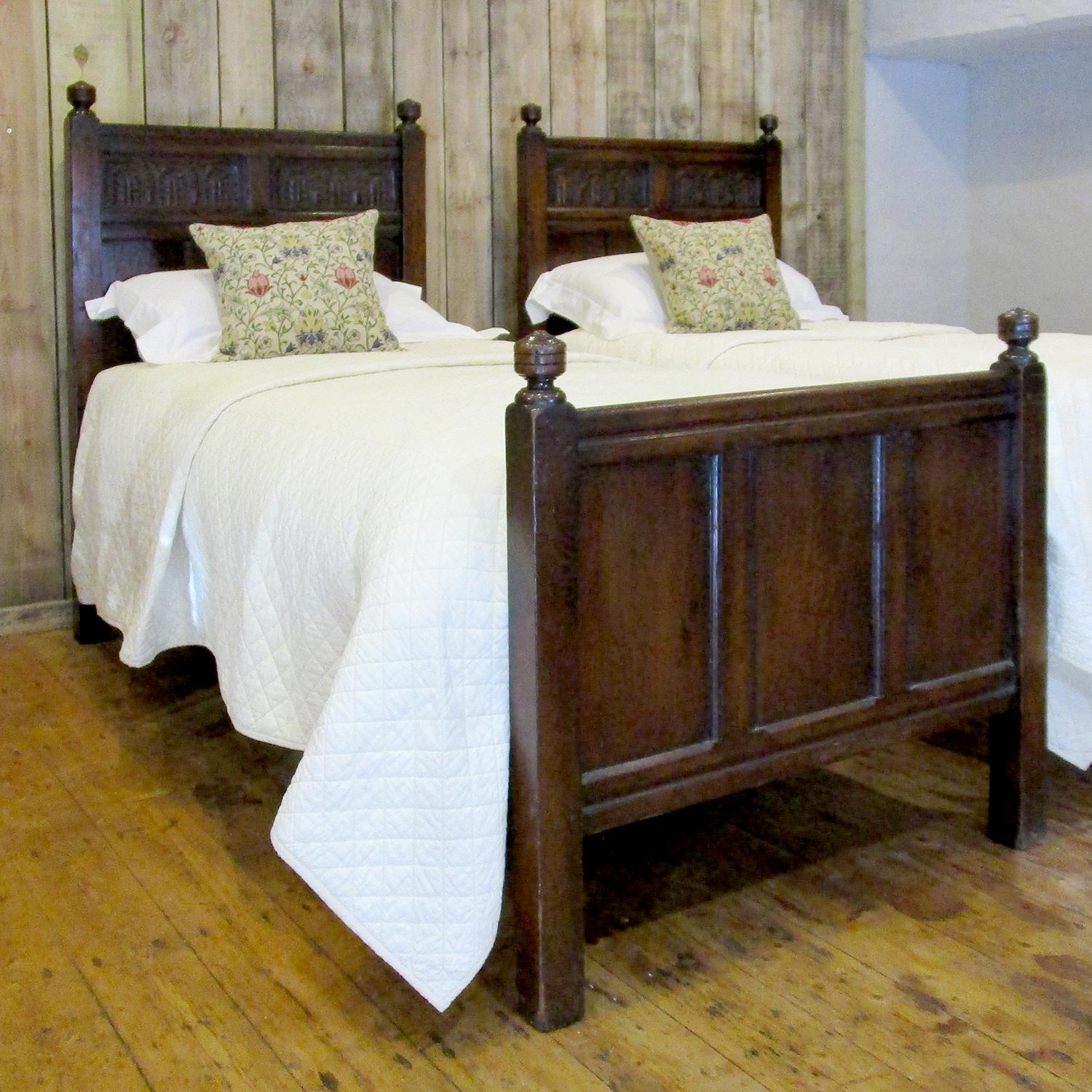 This matching pair of single beds in oak in the Jacobean style were fashioned in the early Twentieth century, circa 1920.

The pair accept standard single size bases and mattresses, 3ft wide by 6ft 3in long (91 cm x 190 cm).
The runners can be
