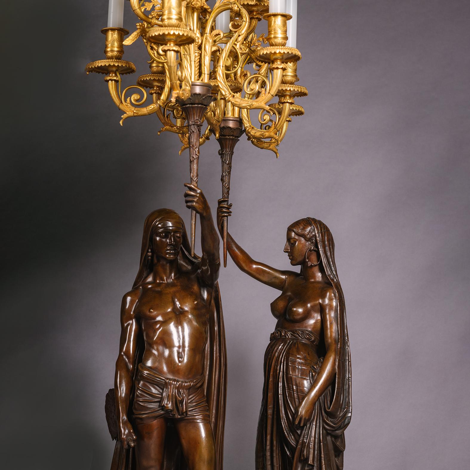 A Pair of Orientalist Patinated-Bronze Figural Torchères, Entitled 'Les Deux Indiens'. Cast by Ferdinand Barbedienne, Paris, From the Models by François-Christophe-Armand Toussaint (1806-1862). 

Signed 'Ad. TOUSSAINT.1850', 'F. BARBEDIENNE.