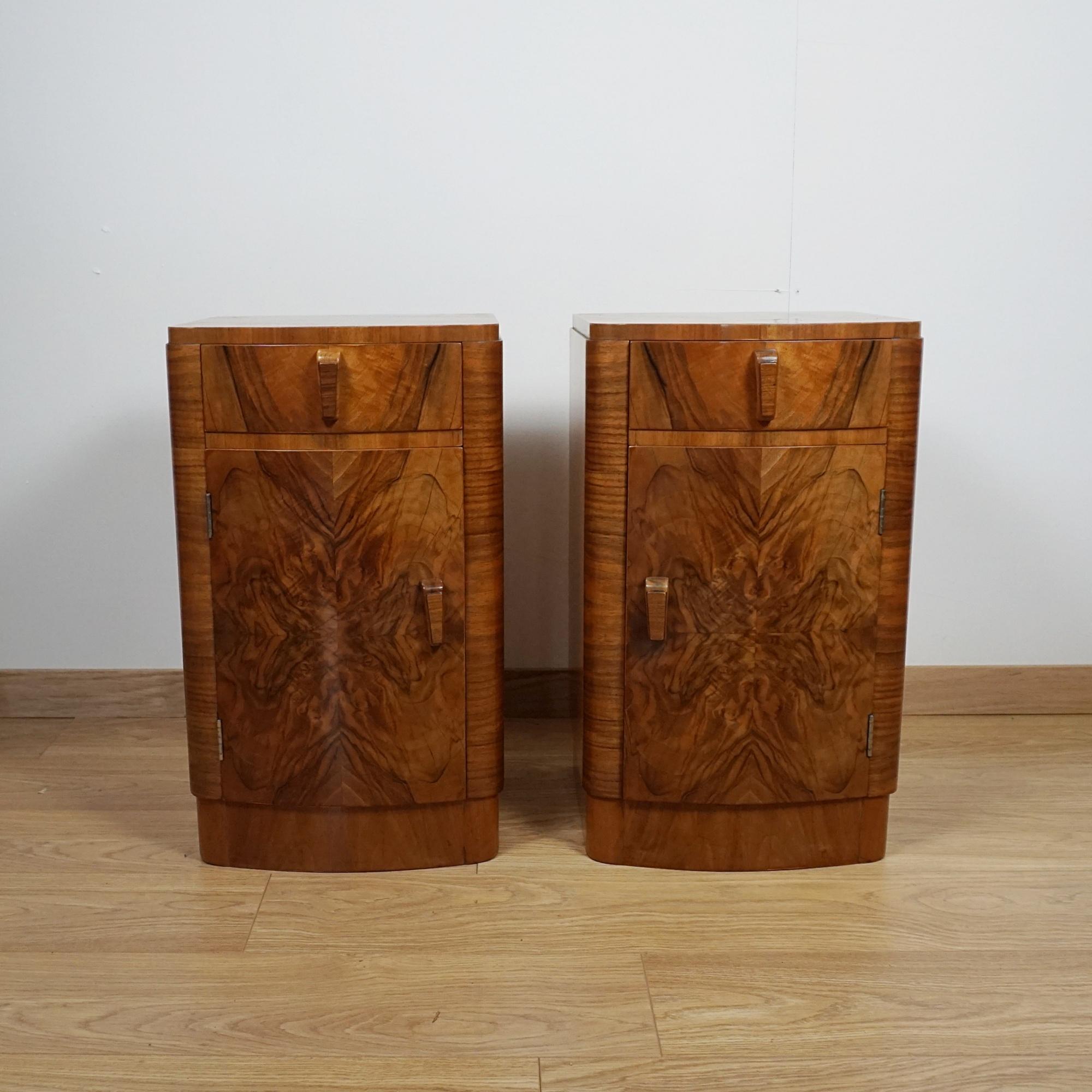 A pair of Art Deco bedside cabinets. Burr walnut and figured walnut veneered. Upper single drawer with a lower cupboard section opening to reveal a single shelved interior. Original walnut handles.

