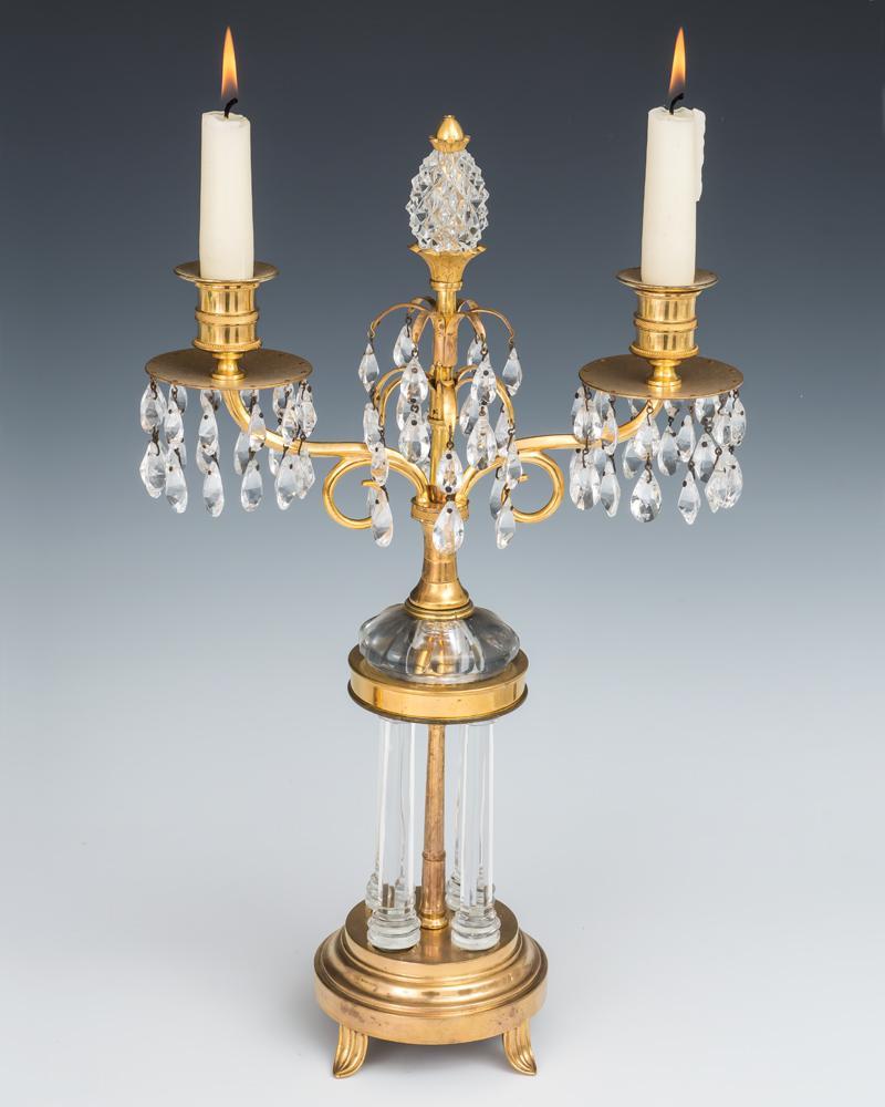 A pair of Regency candelabra of temple form on ormolu bases mounting four cut glass columns, the base issuing two scroll arms supporting candle nozzles and drip pans the centre with ormolu sprays terminating with a cut glass pineapple, the