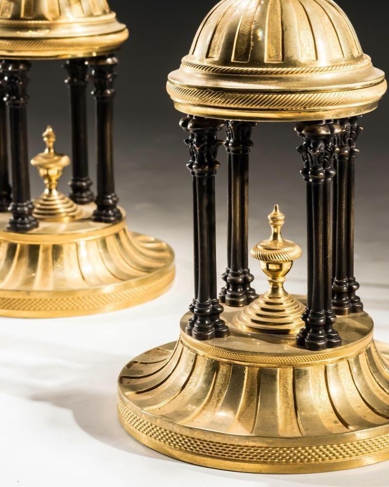 A pair of Georgian temple candlesticks with fine ormolu bases containing bronzed columns surmounting a diamond cut glass egg finishing with a van dyke pan and candle nozzle hung with finely cut pear drops.
