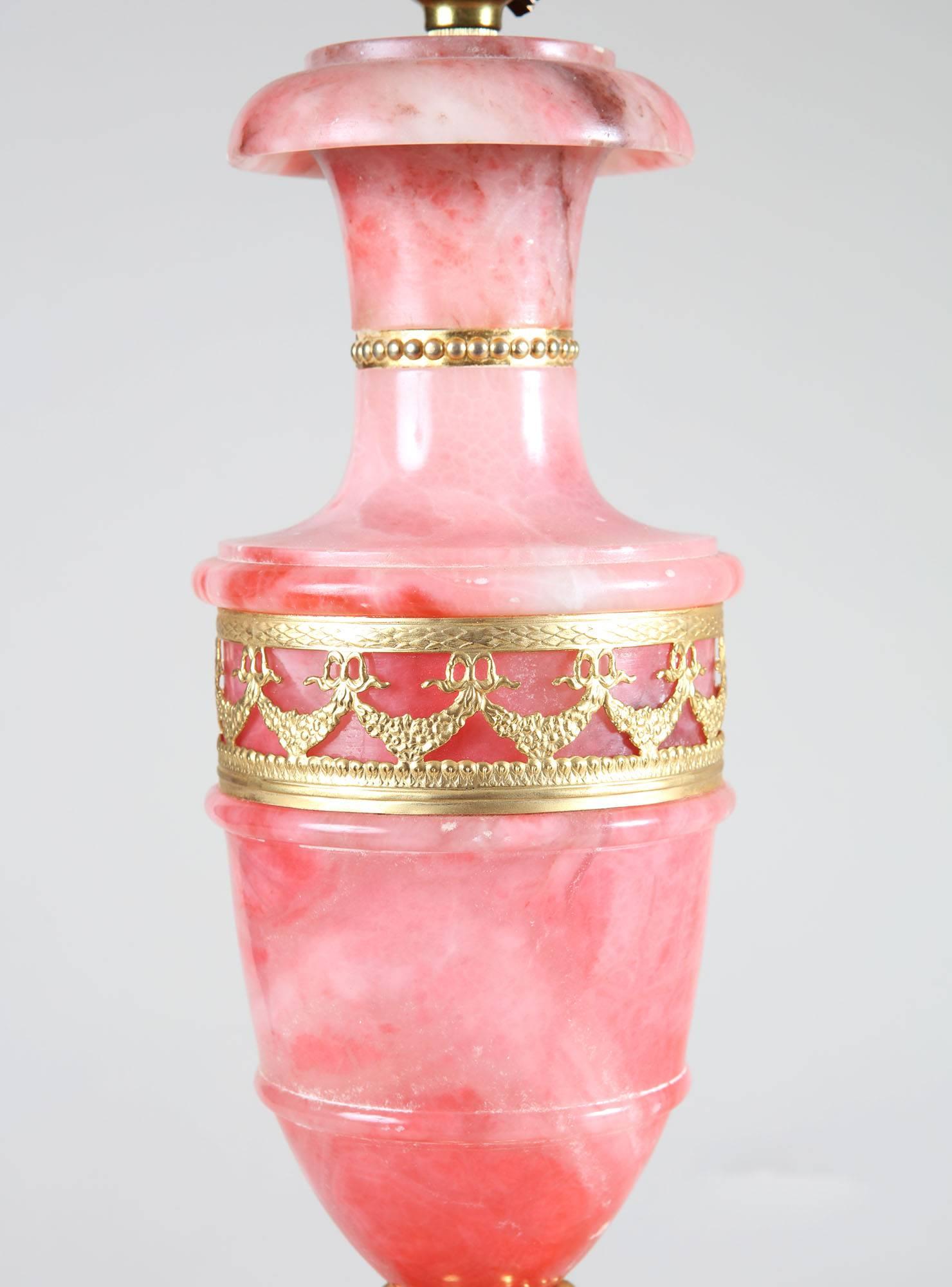 A pair of ormolu-mounted pink onyx lamps with red tasseled shades

Measure: 42 cm high (to the top of the column), 
77 cm high (including shade).