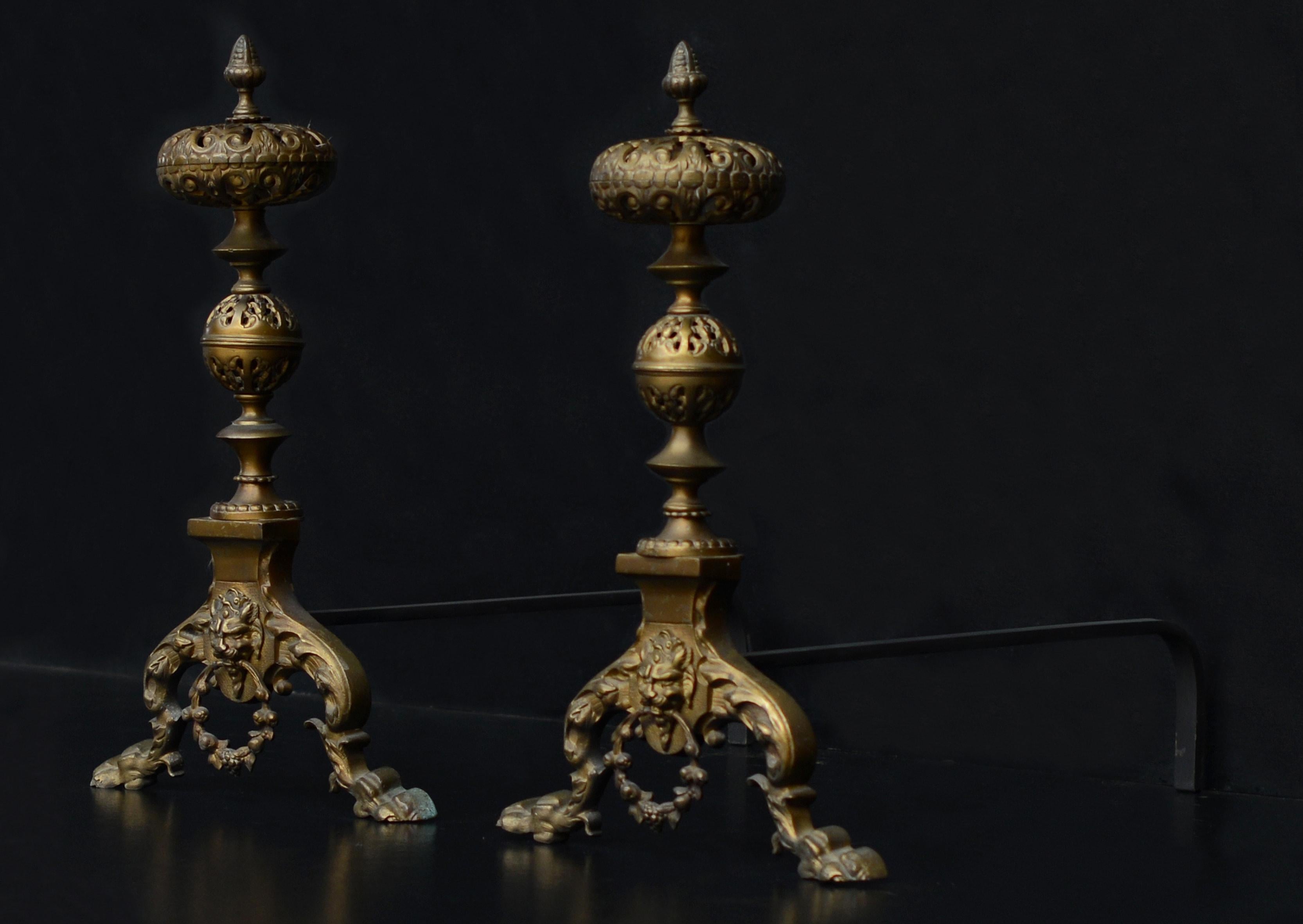 A pair of ornate brass firedogs. The paw feet with mask and ring handle to centre, surmounted by pierced brass balls to shafts. Currently not polished to high shine, but could be polished if required.

Measures: Height: 535 mm 21 