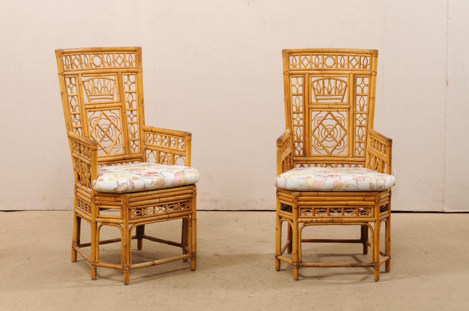 A pair of ornate bamboo armchairs with upholstered seat cushions. This vintage pair Thai chairs feature bamboo frames, which have been constructed with intricately designed panels found throughout their backsides, arm rests, and skirting. The top