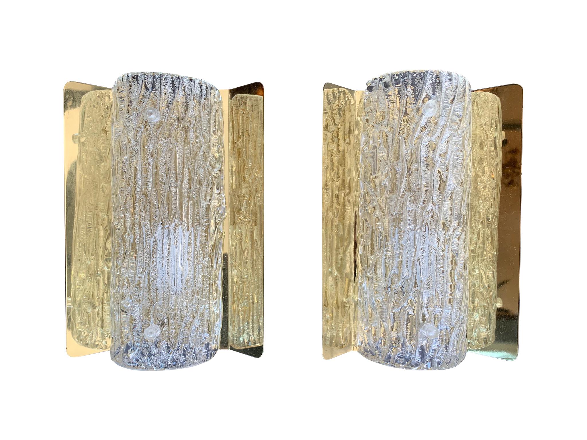 A pair of Orrefors glass wall sconces by Falkensberg Belysning, Sweden, with textured clear glass shade mounted on a flared back plate with a single bulb fitting. Re wired with new fittings and PAT tested and with original labels on reverse.