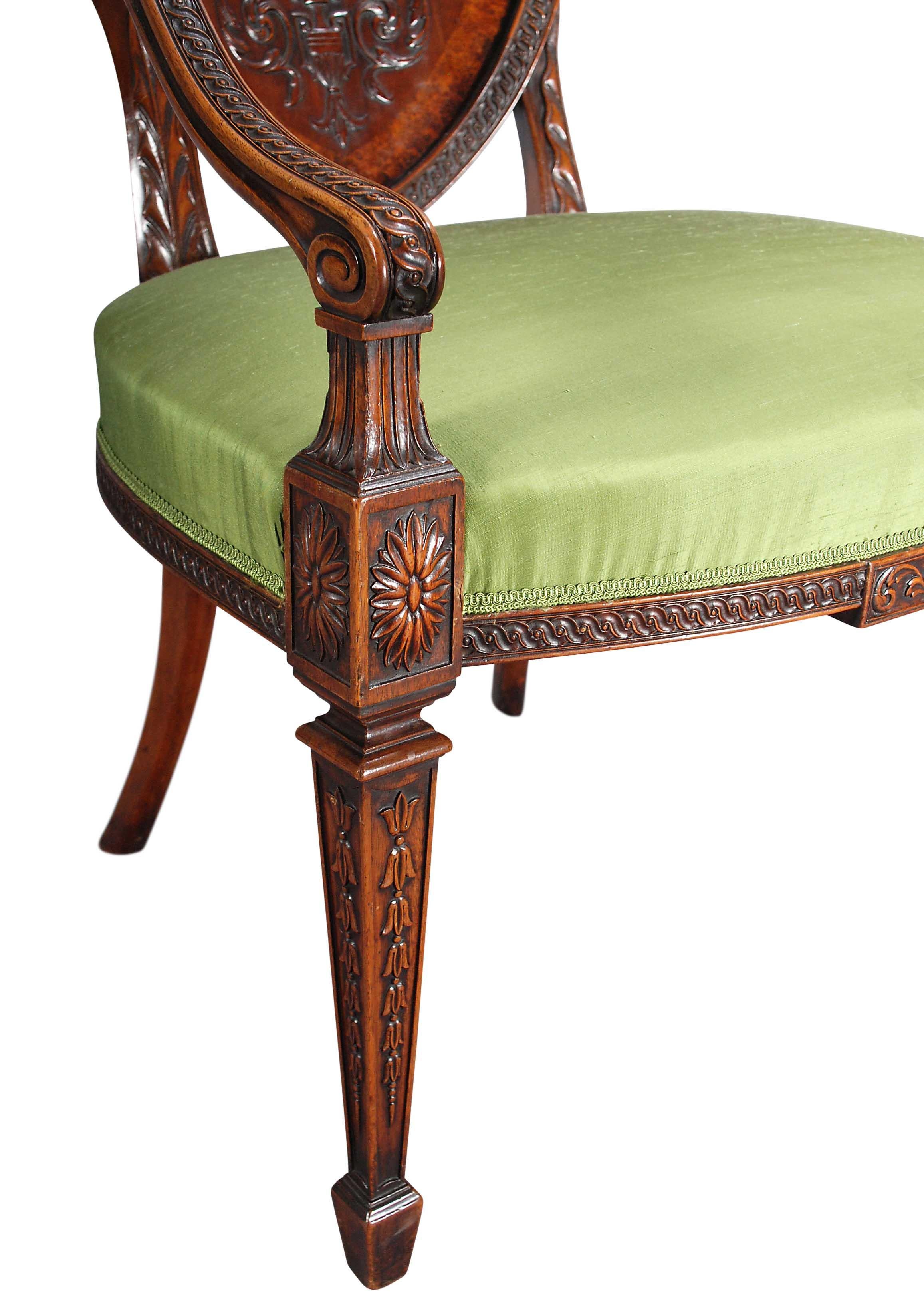 Ein Paar großformatige Mahagoni-Sessel mit Schnitzereien und Intarsien. Die schildförmigen Rückseiten werden von einem gemalten Wappen in einem ovalen Wulst zentriert. Das Wappen ist von applizierten Schnitzereien umgeben, die verschiedene